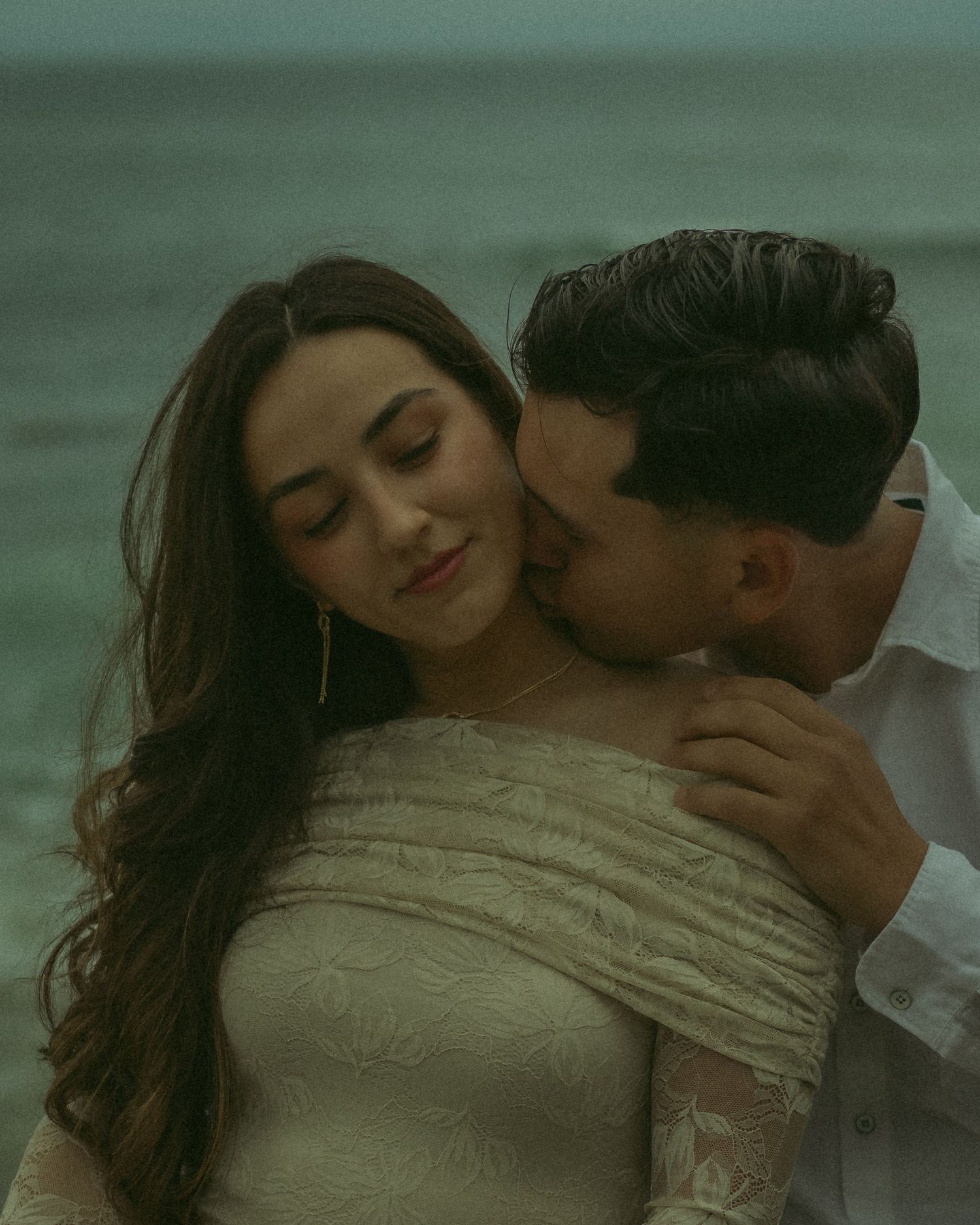 Husband giving his wife a romantically intimate kiss on the neck.