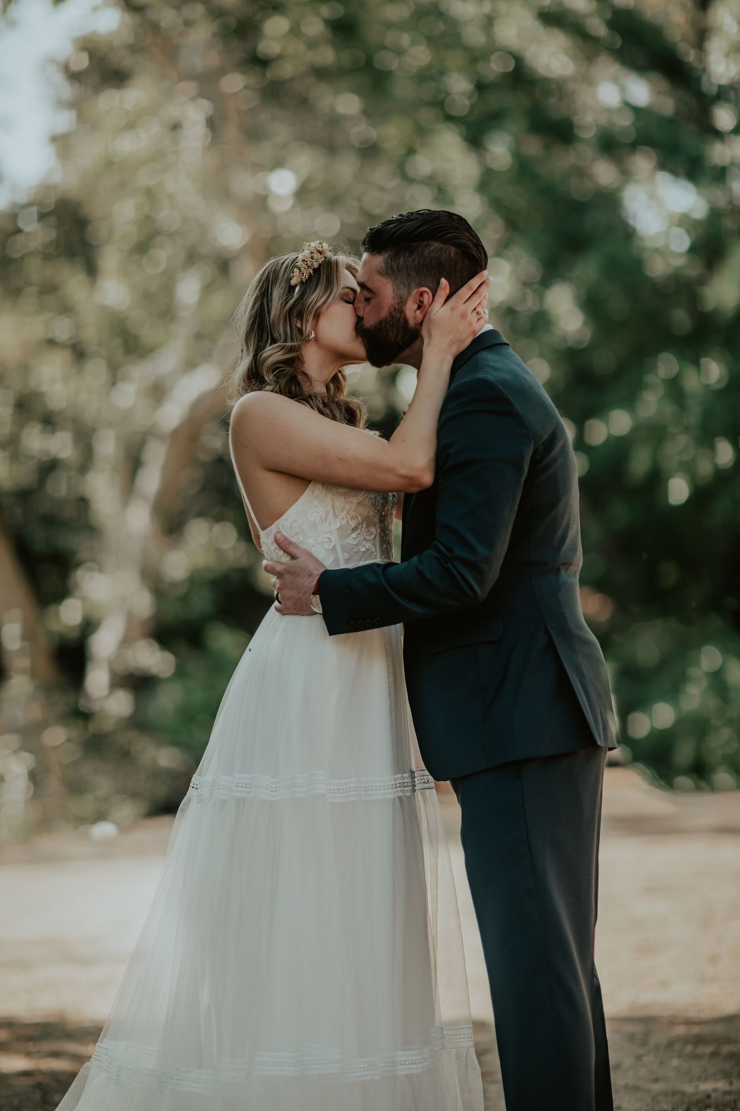 A romantic wedding couple shares a tender kiss away from the reception and guests