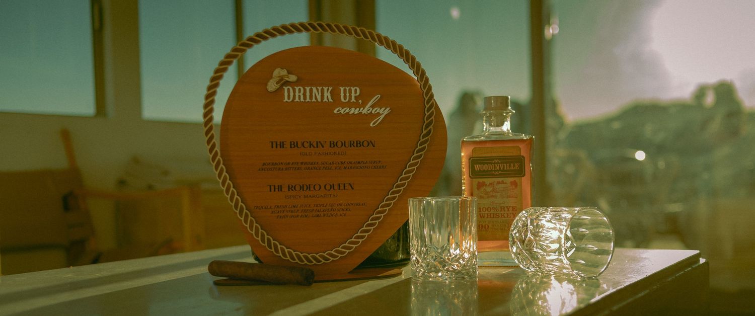 Bottle of whiskey and glasses sit side by side in warm sunlight at the Elopement bar