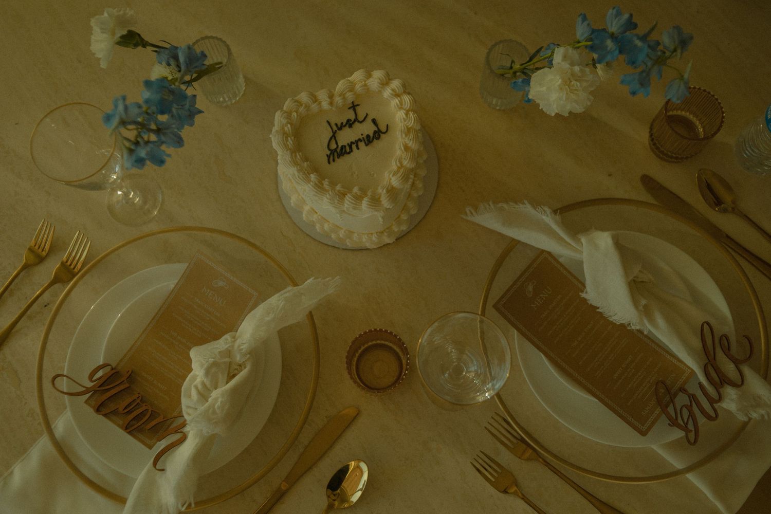 Overhead view of a dining table setup with vintage blue decorations and ornate white plates on a gold background.