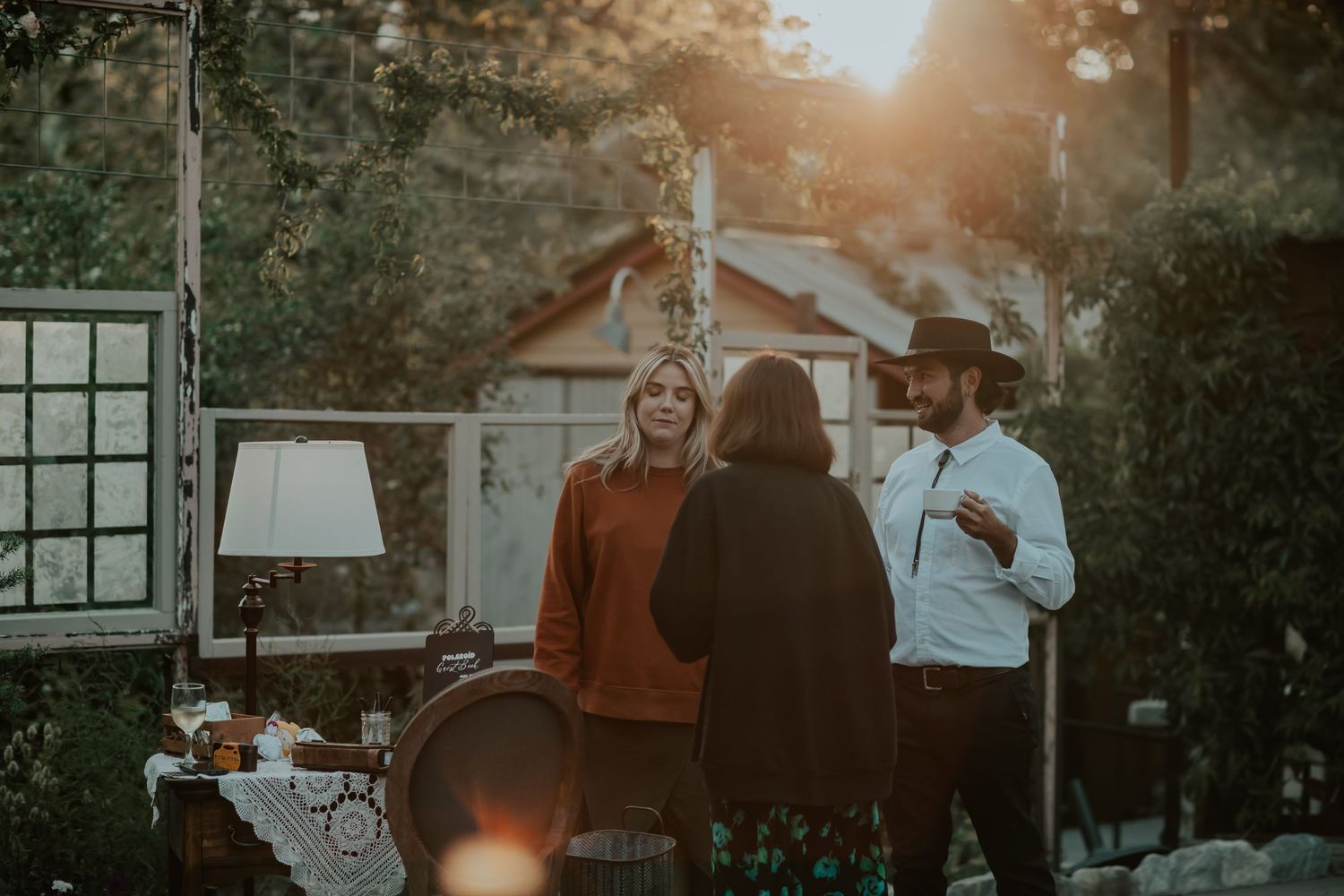 Guests enjoying a cinematic outdoor wedding venue with warm sunset lighting and lamps.