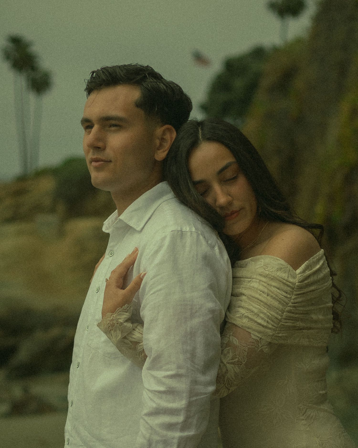 Couple romantically embracing on the beach on a overcast day.