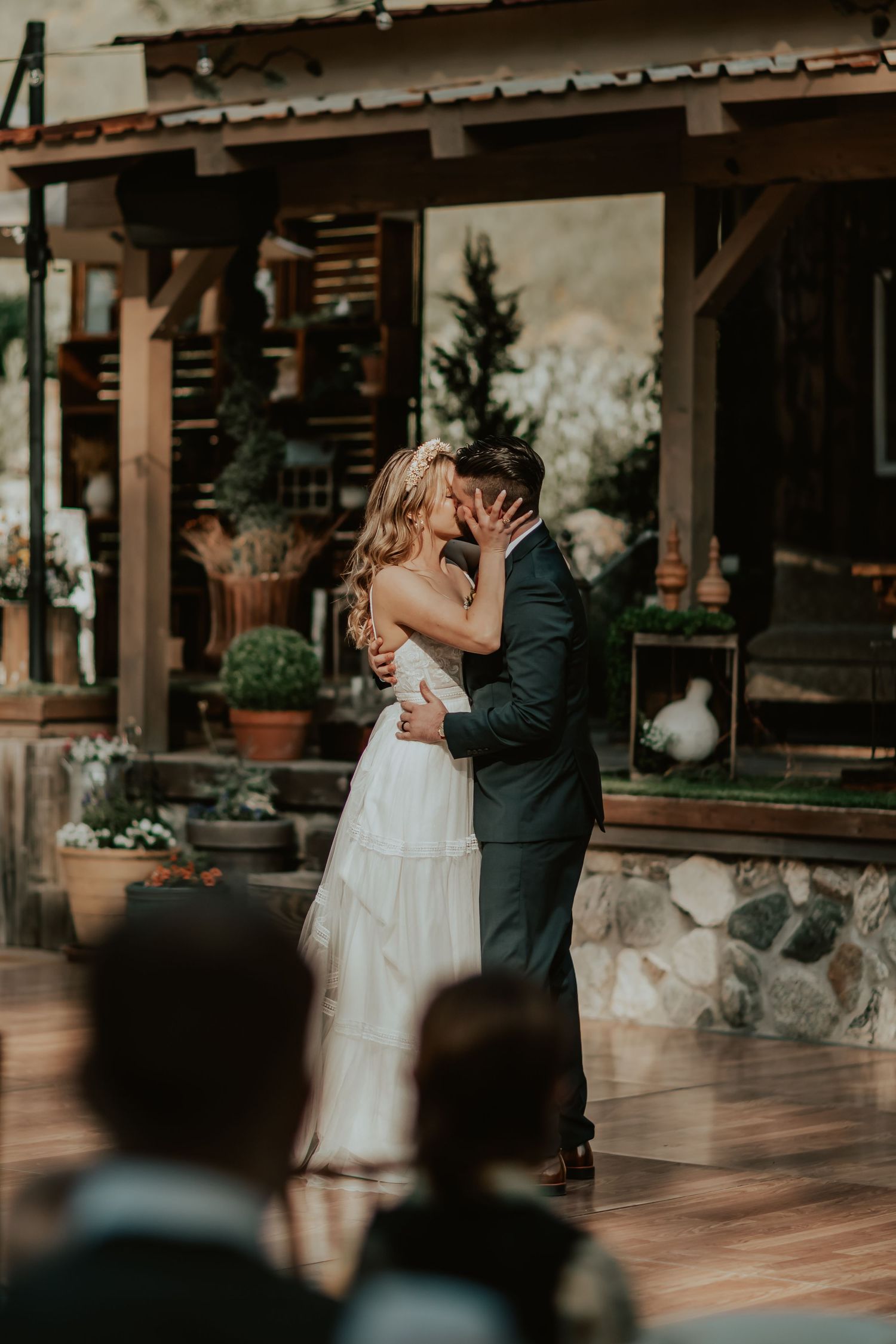 A romantic couple shares their first dance as newlyweds on a rustic wooden porch during their intimate outdoor wedding.