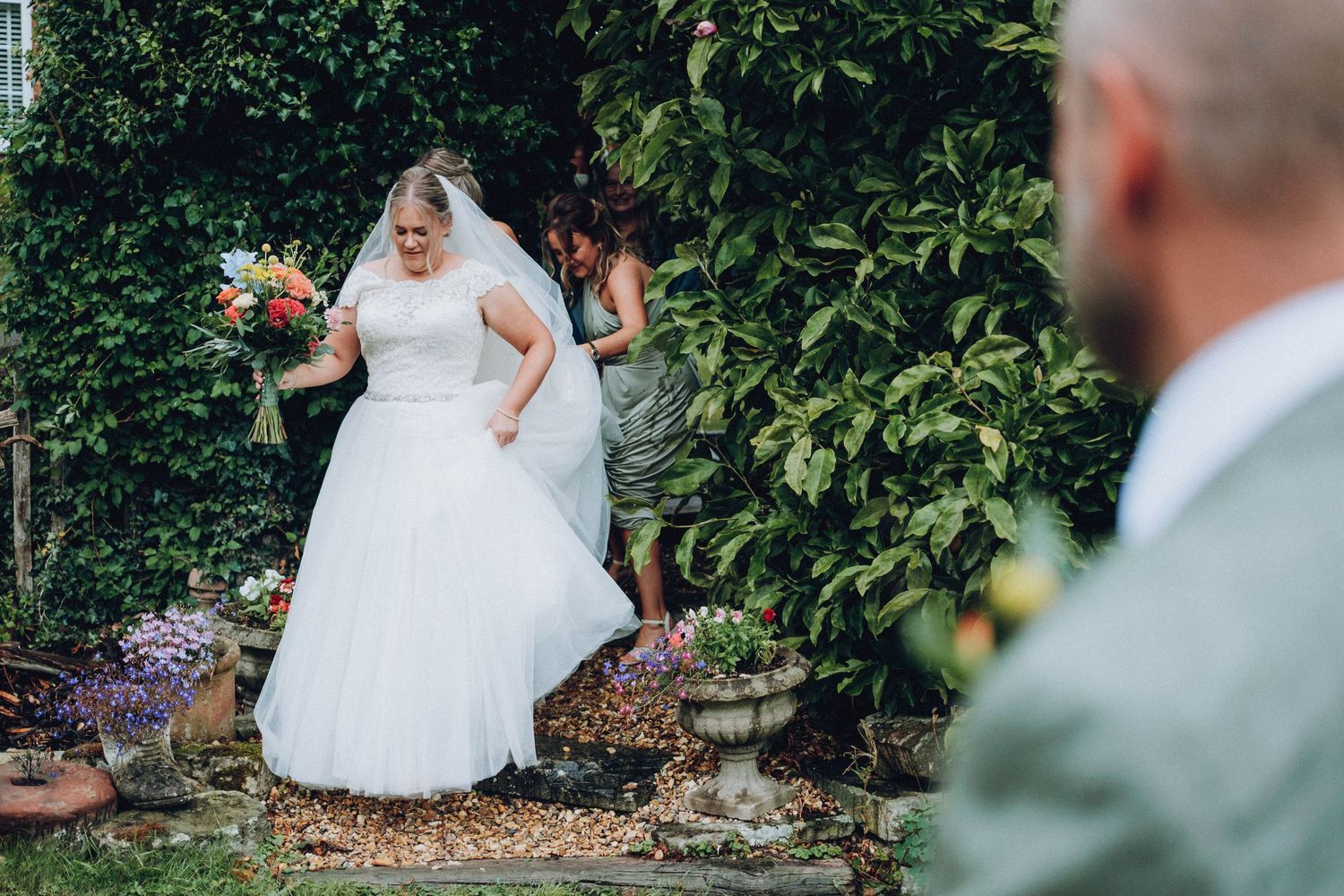 Couple in wedding attire enjoying a private moment together in a lush garden setting during their special day.