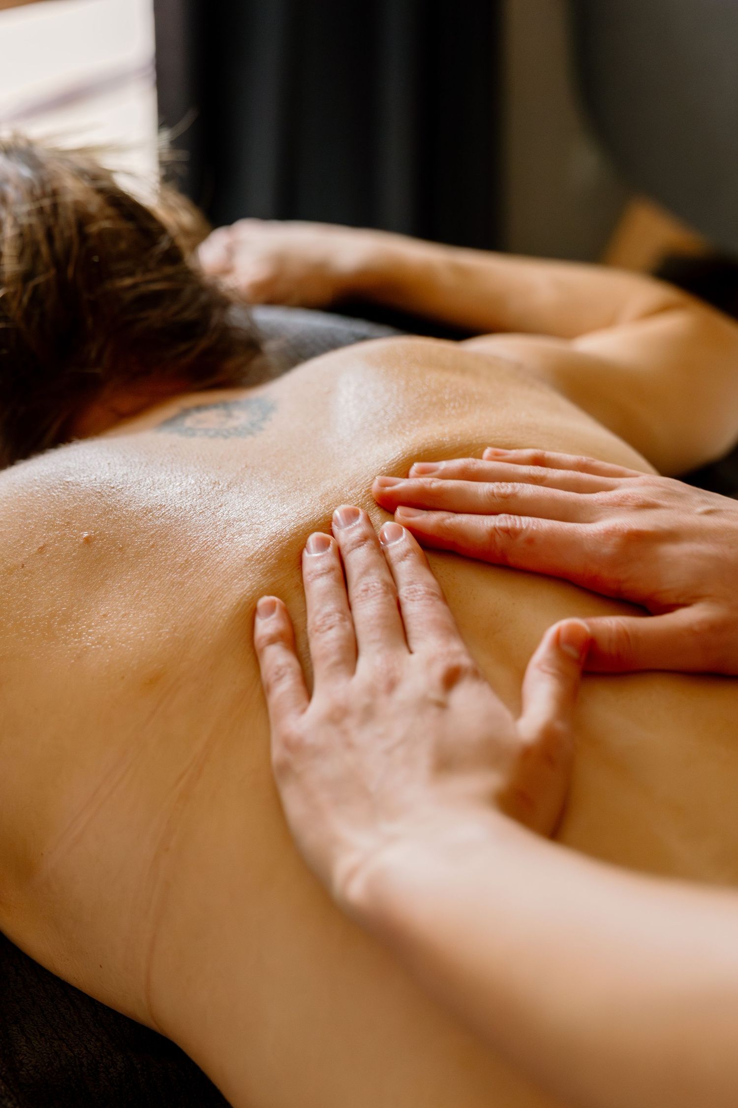 Close up of hands performing therapeutic massage on back muscles at spa during relaxation treatment.