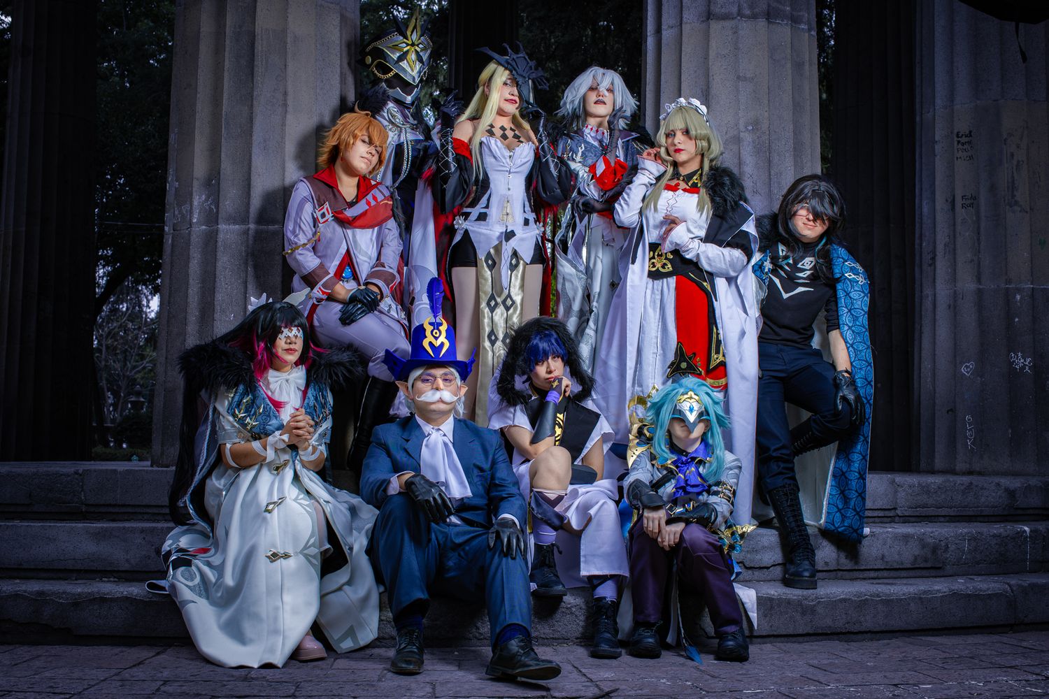 Cosplay group in elaborate costumes posing on stone steps at night.