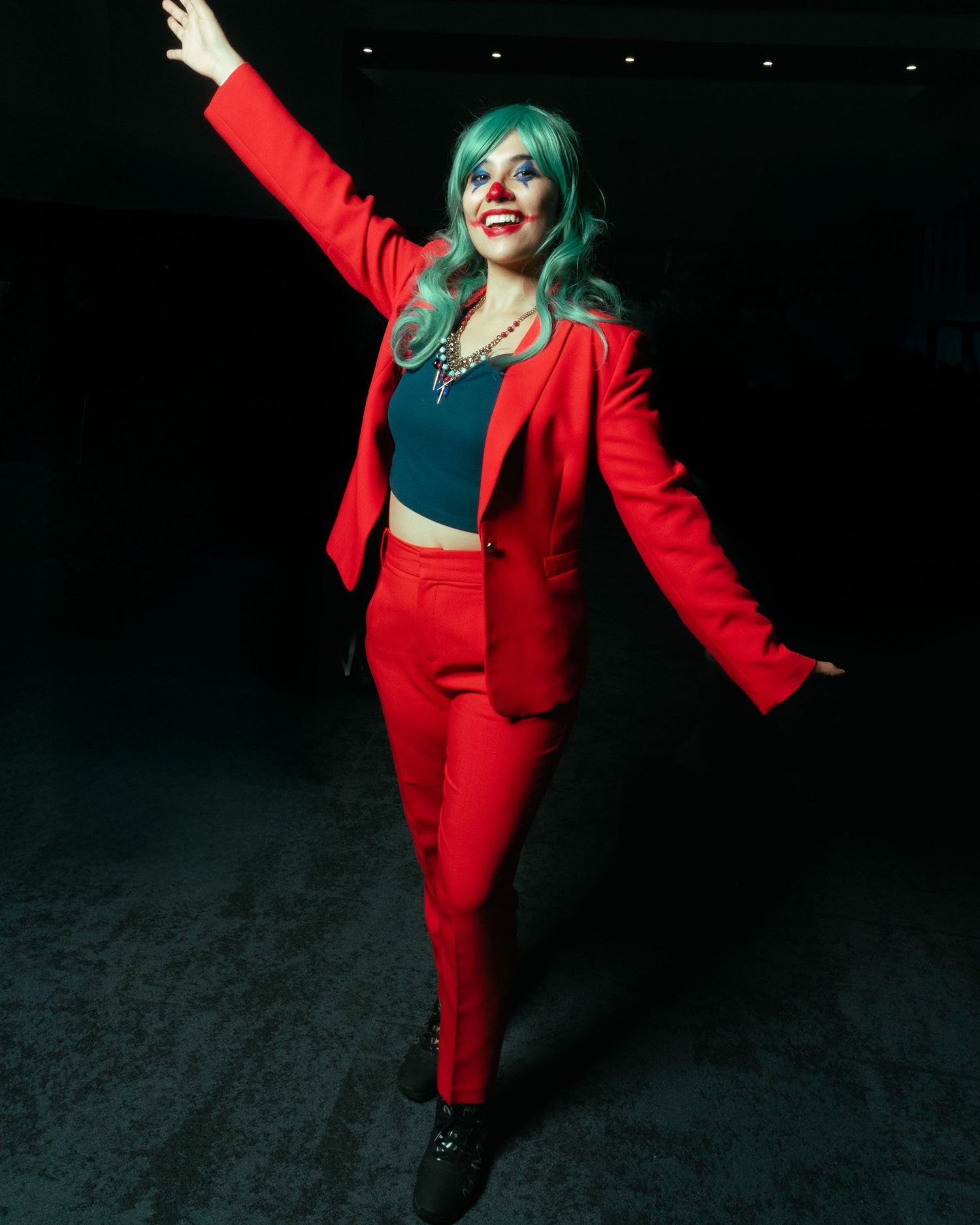 A fashionable red pantsuit ensemble with teal hair styled in a lively dancing pose.