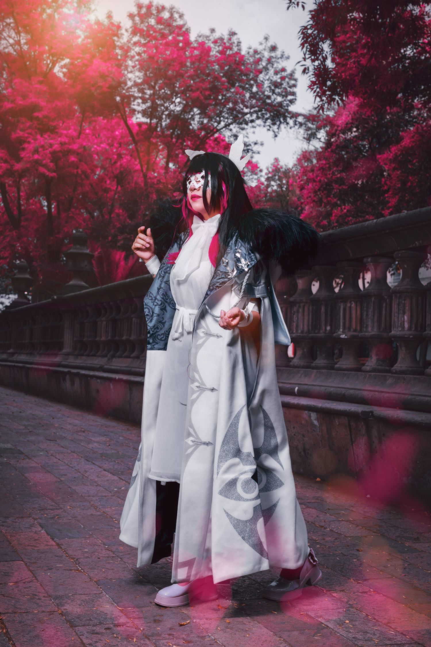 Fantasy cosplay photoshoot in a garden with vibrant red trees and gothic stone balustrade under dramatic lighting.