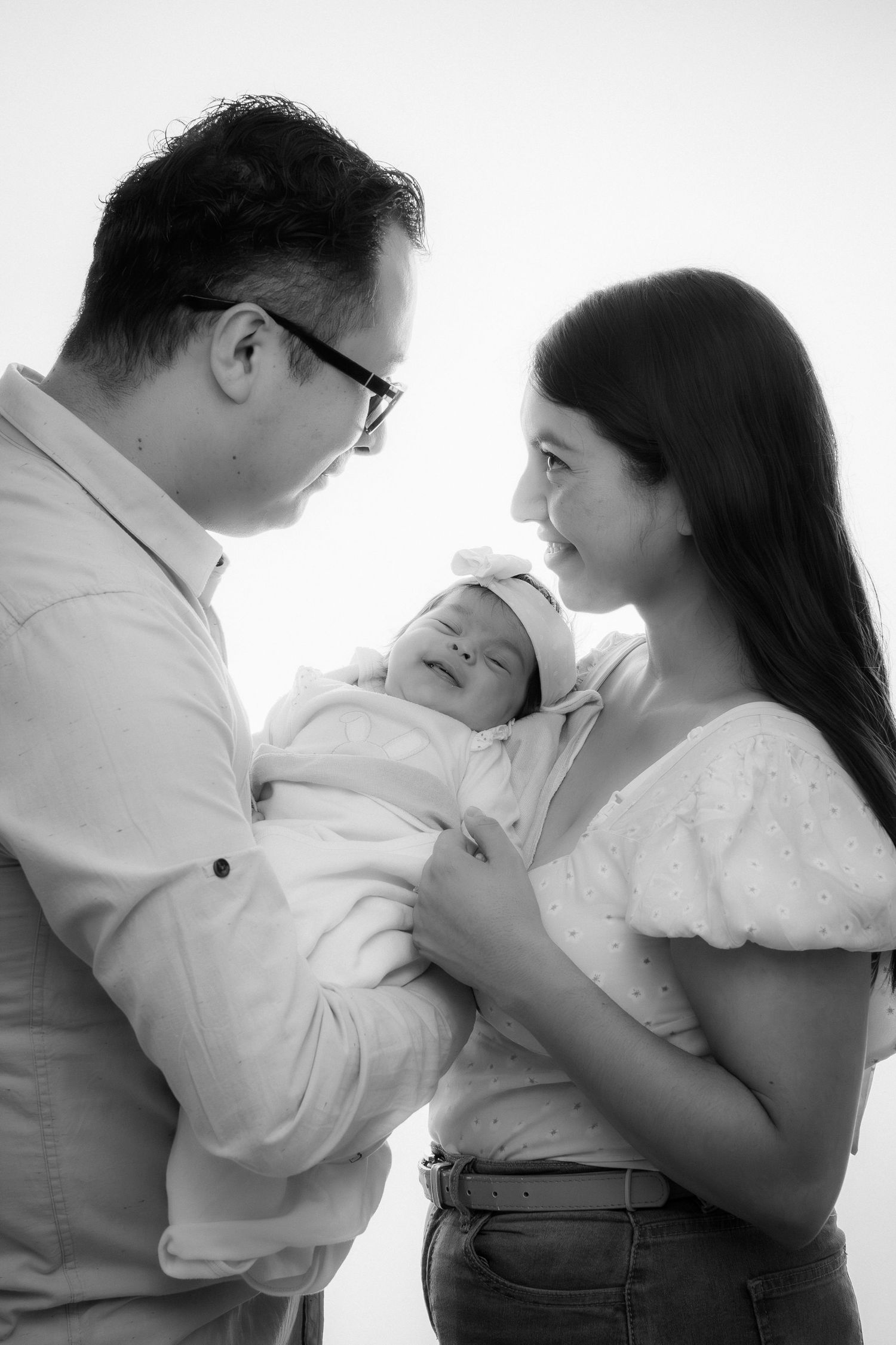 Black and white portrait of parents tenderly holding their newborn baby.