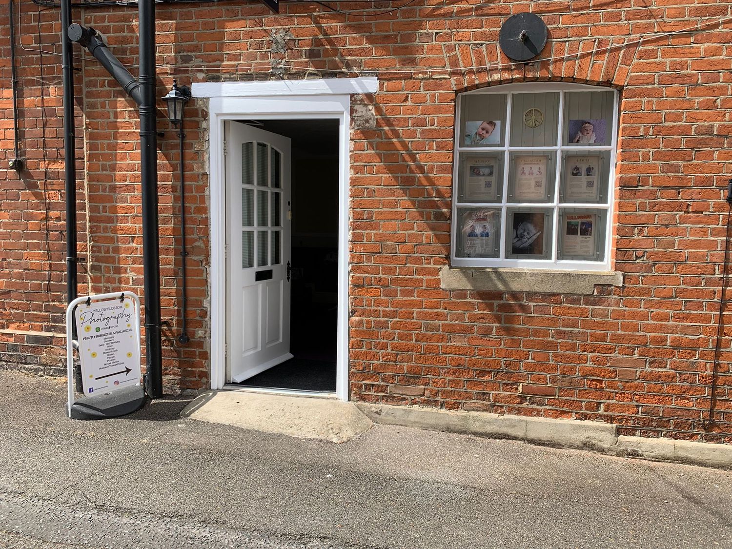 Red brick wall with white door frame and window installation.