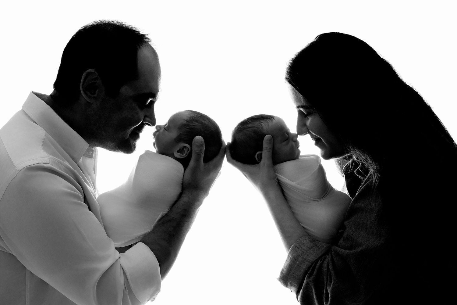 Black and white silhouette portrait of parents with babies.