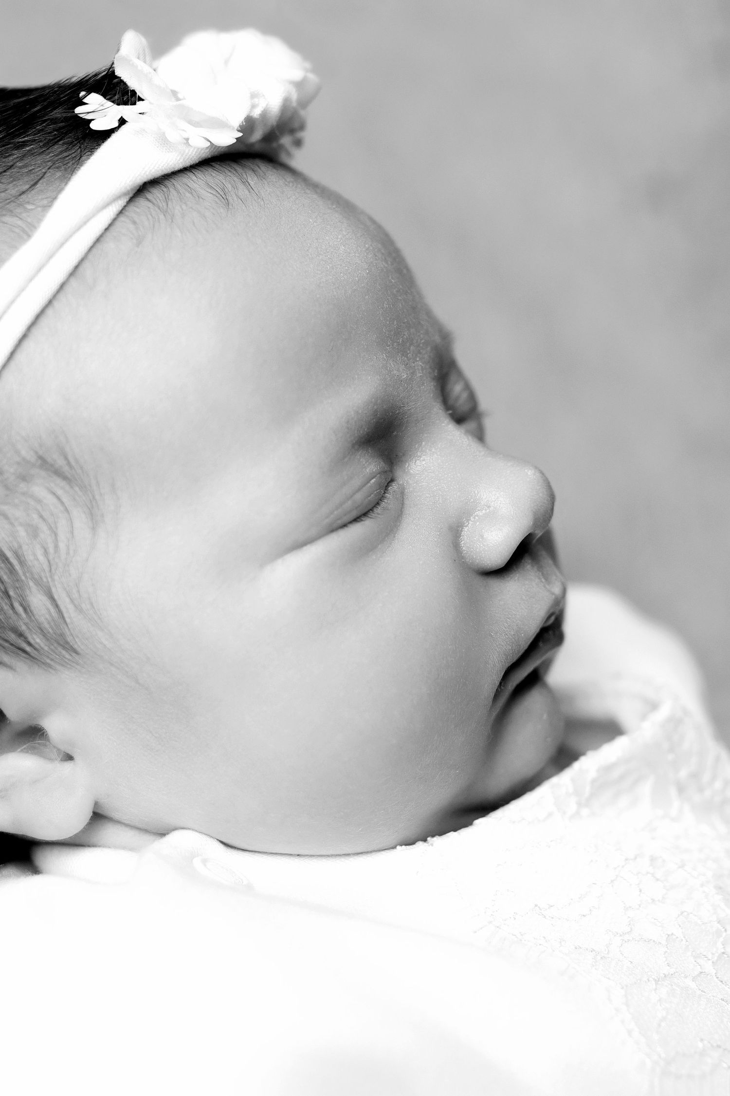 Black and white portrait of sleeping newborn wearing white headband.