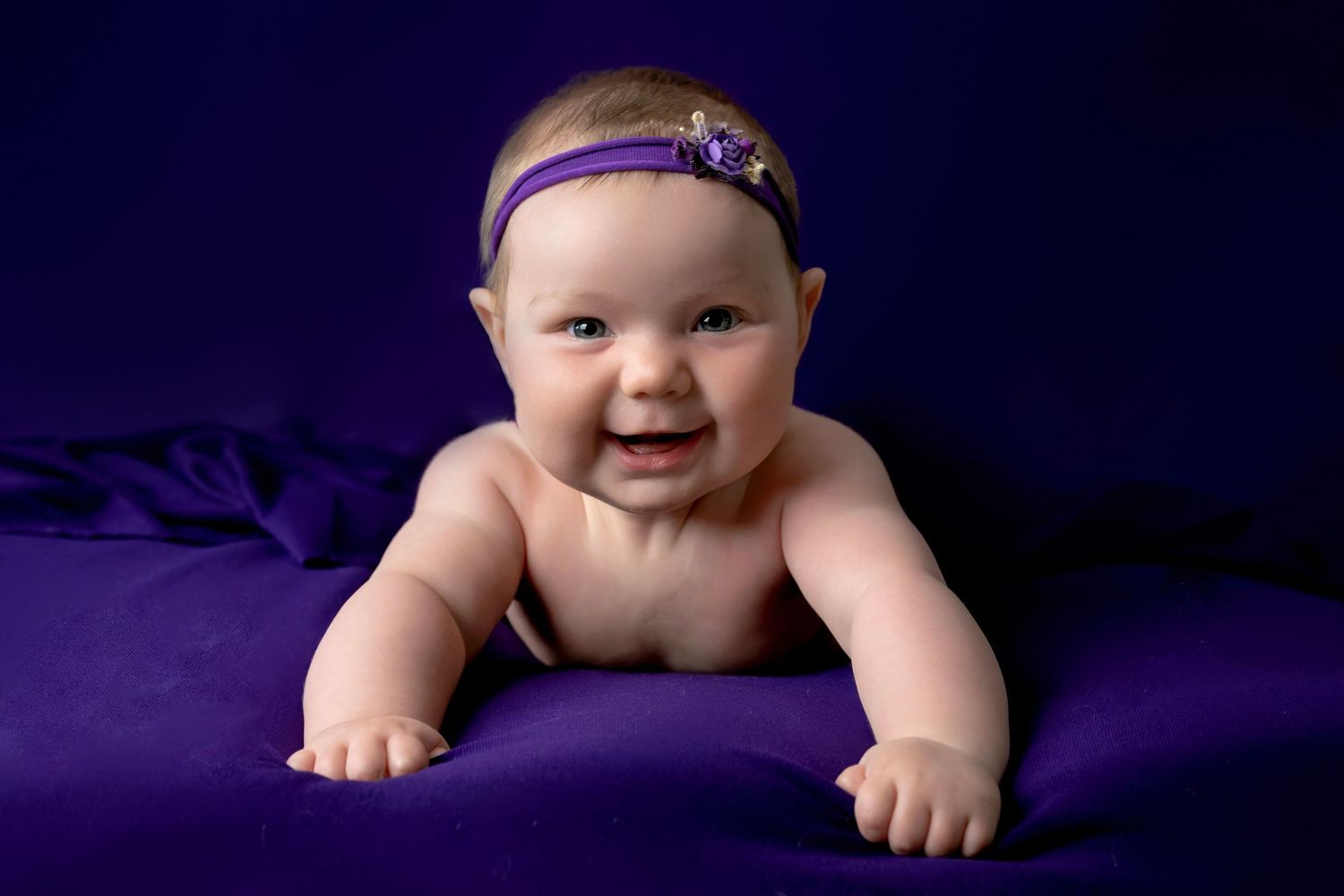 Studio portrait on deep purple backdrop with matching headband accessory.