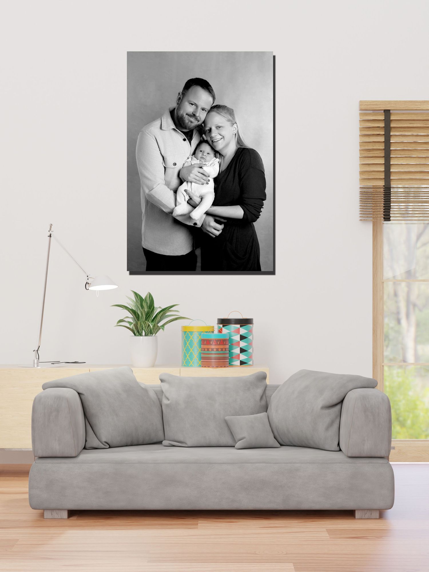 A modern living room with a gray sofa and wall art displayed above, accompanied by indoor plants.