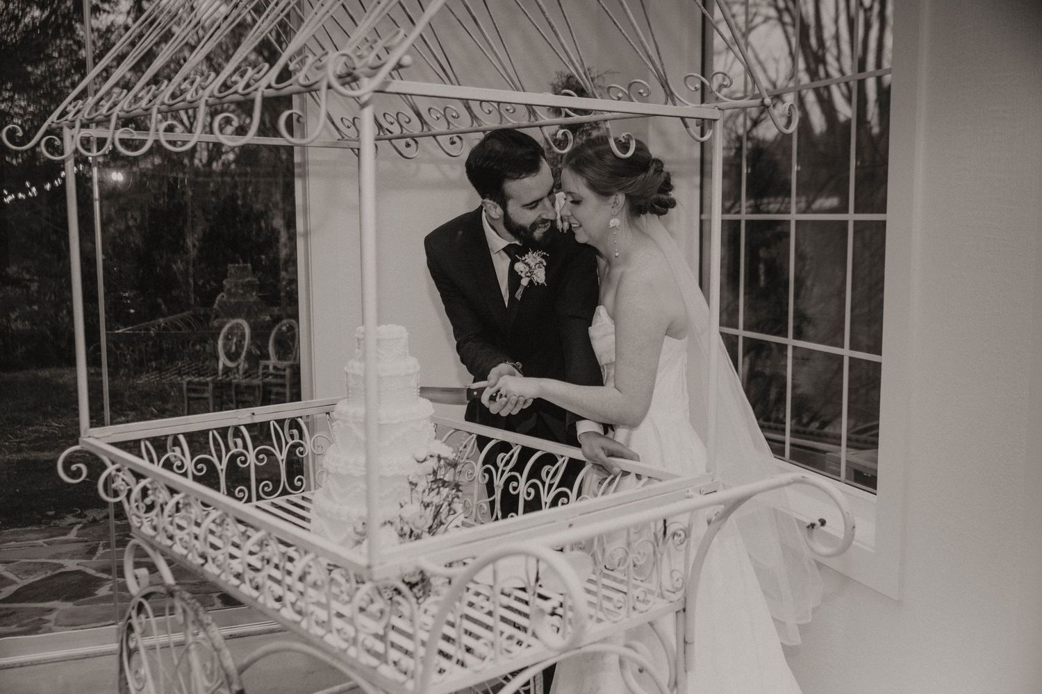 A romantic black and white wedding moment captured in a vintage-style gazebo with ornate ironwork details.