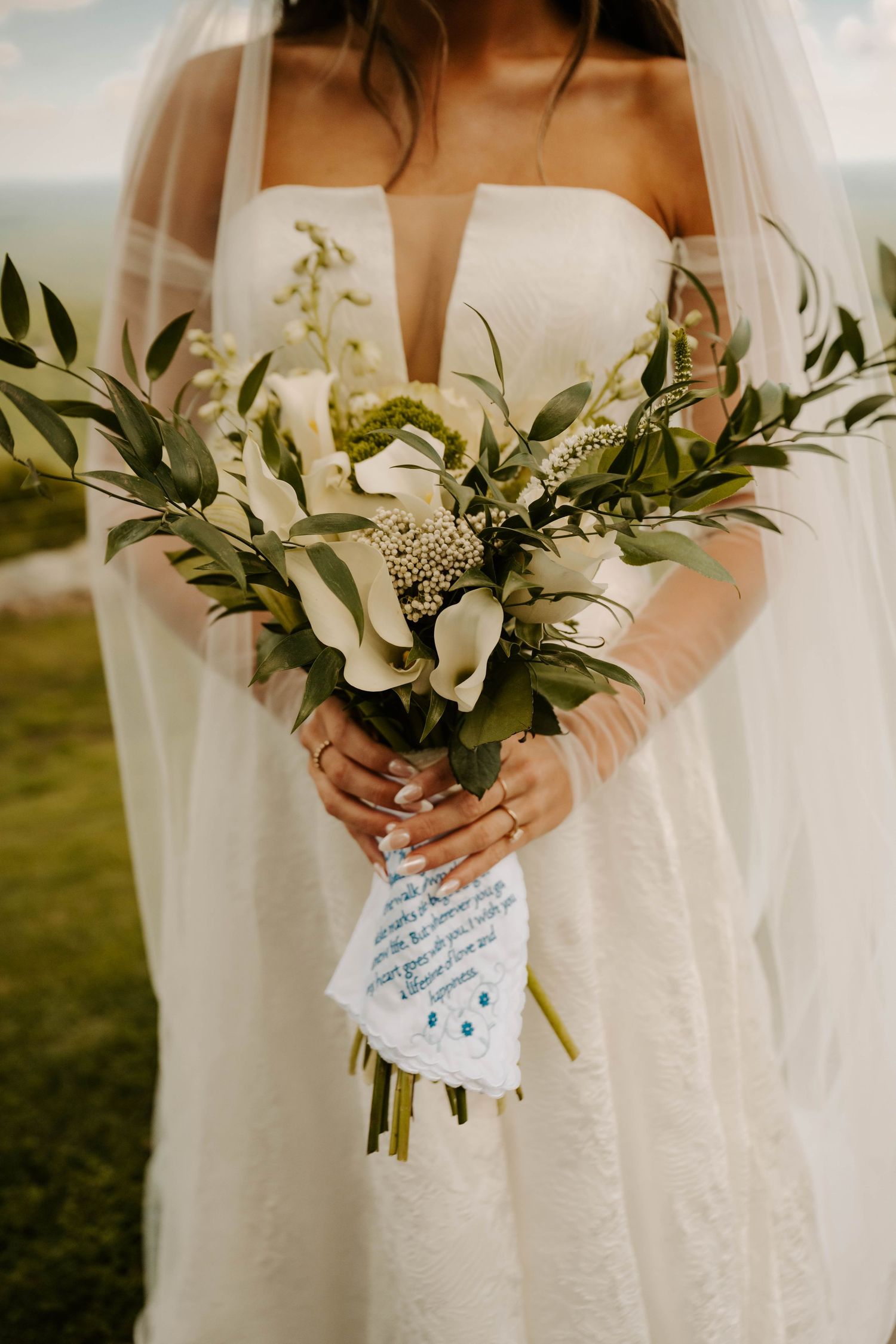 Close-up shots of a bridal bouquet with delicate white lilies and greenery against a white wedding dress.