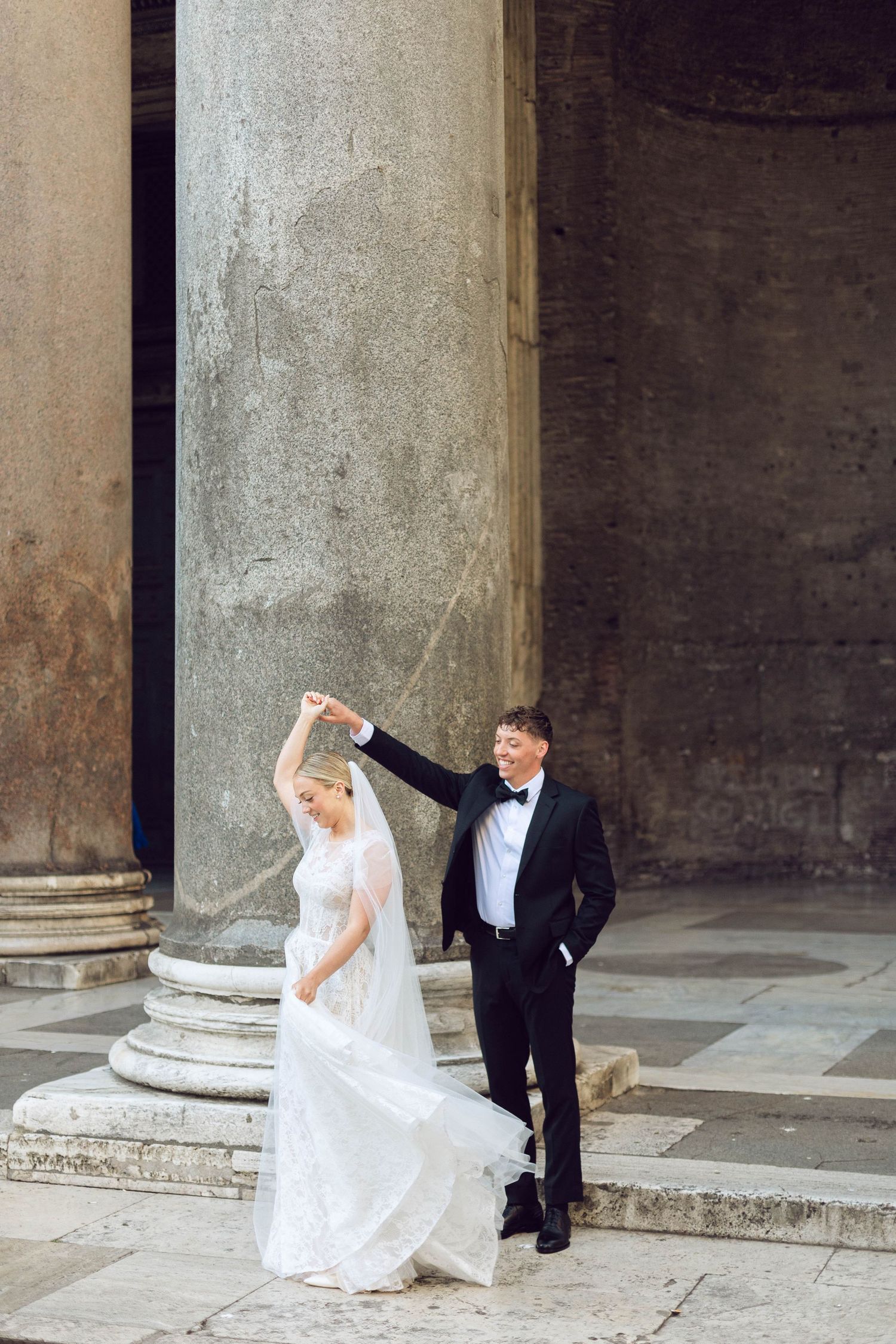 A romantic wedding dance pose on historic stone steps with classical columns in the background of rome italy.