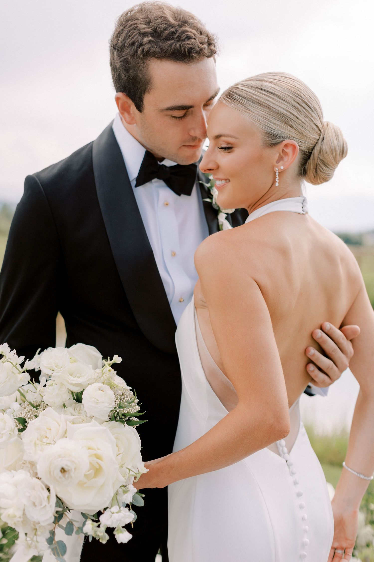 Intimate wedding portrait with white roses and elegant attire.