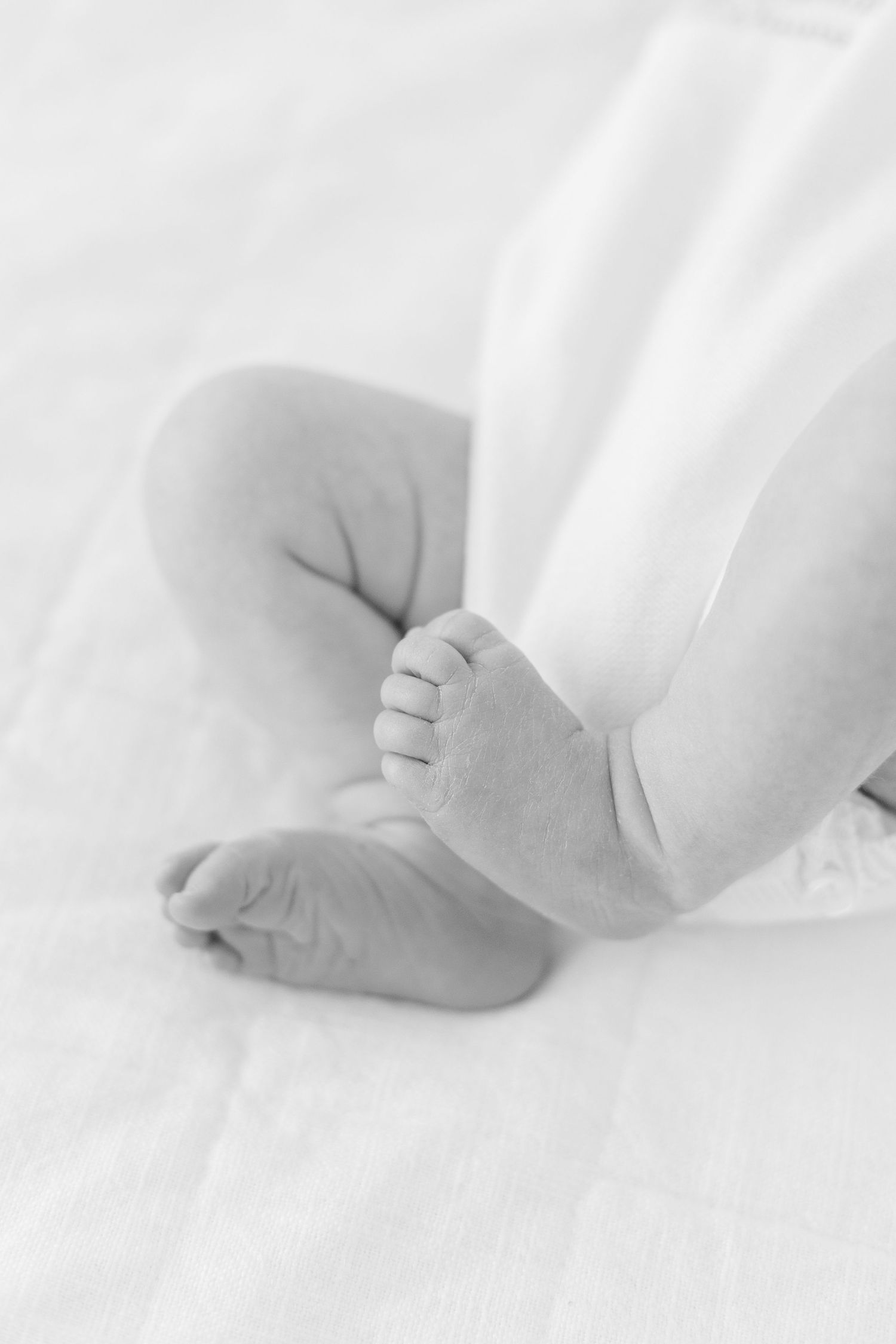 Close-up of tiny newborn baby feet on white bedding.