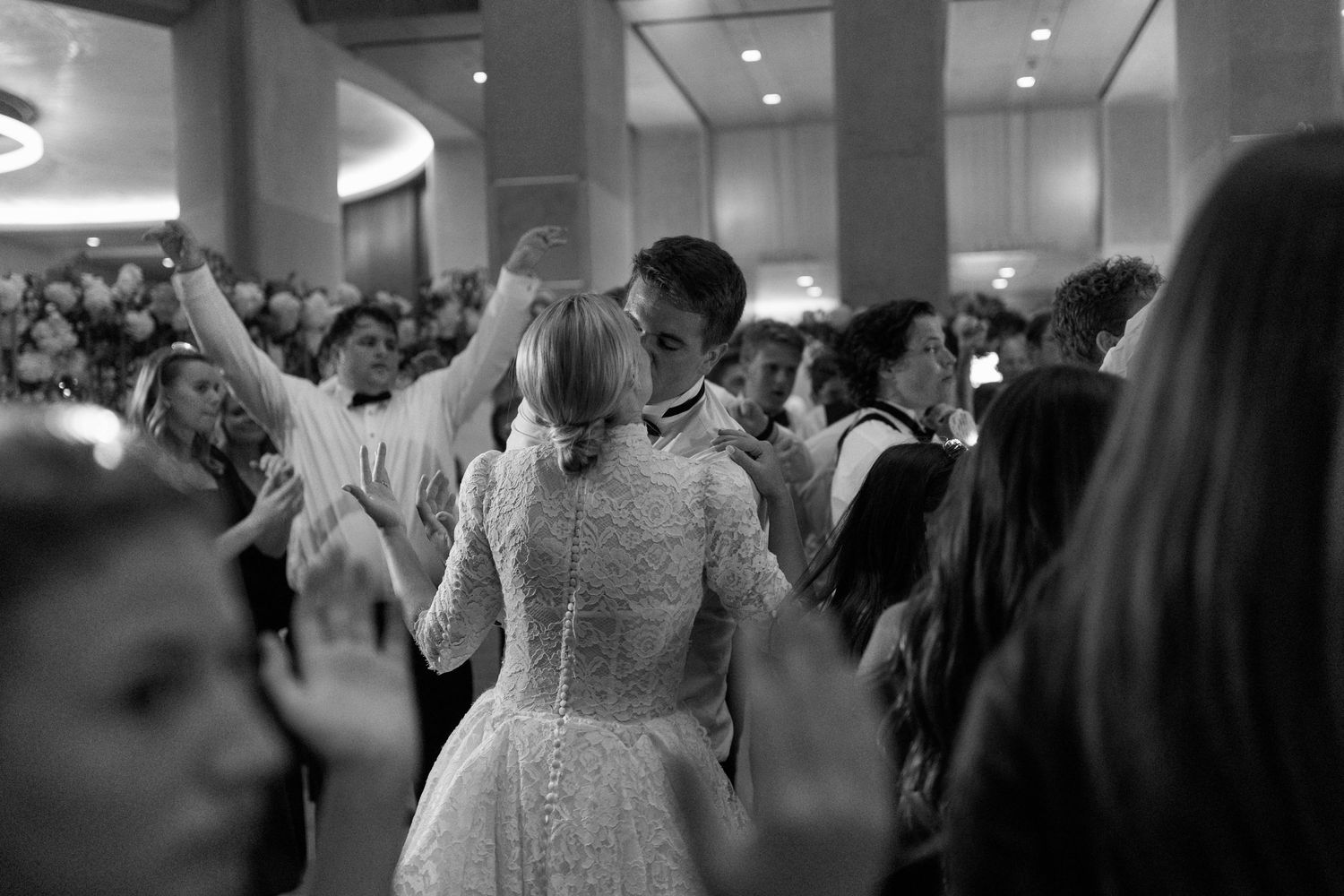 Wedding reception dance floor filled with celebratory guests in formal attire.