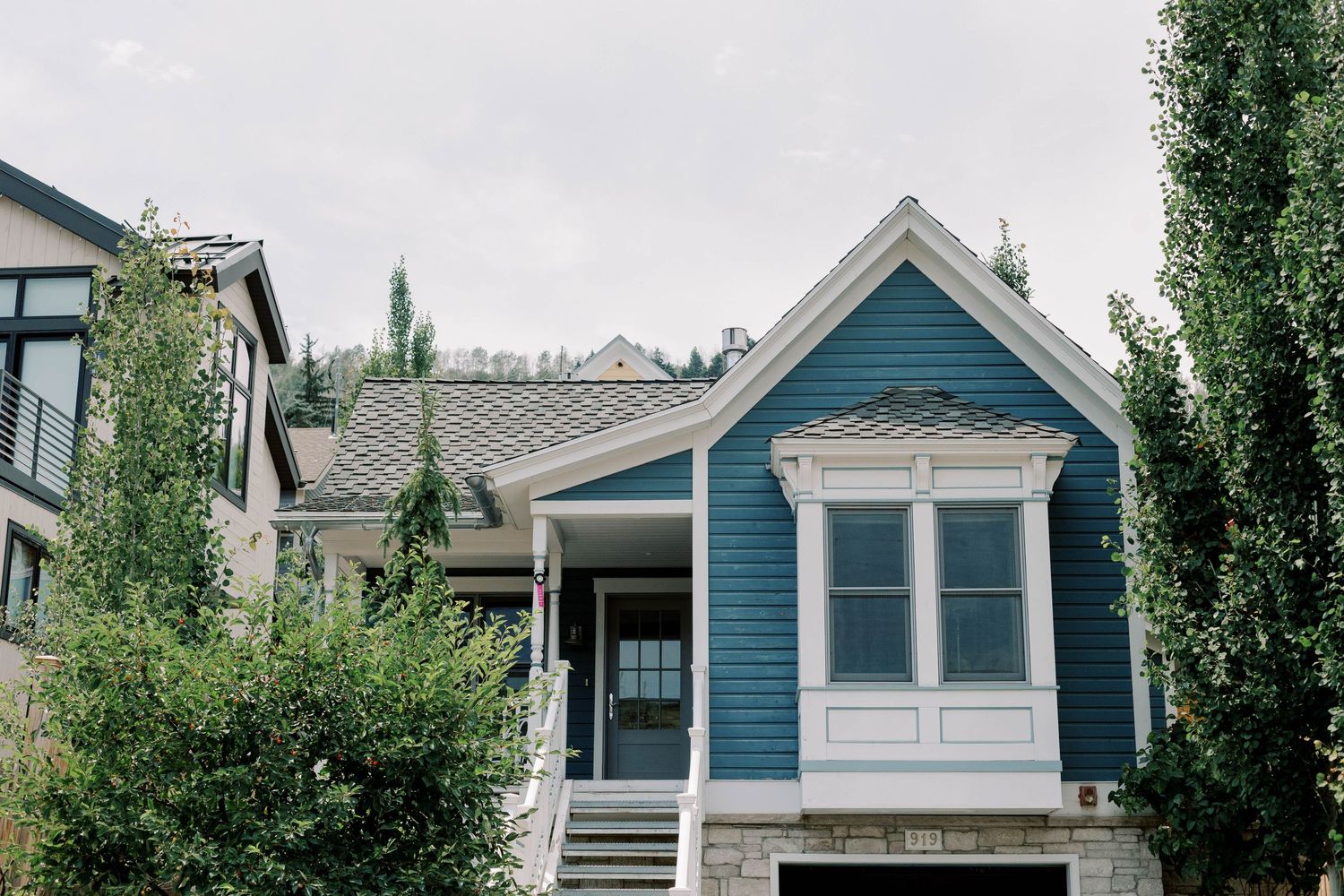 A charming blue Victorian style house with white trim and a front porch.