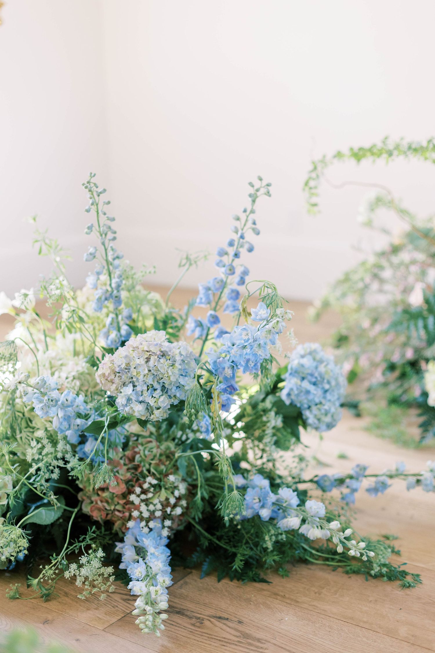 An ethereal floral arrangement featuring blue delphiniums, white hydrangeas and delicate greenery.