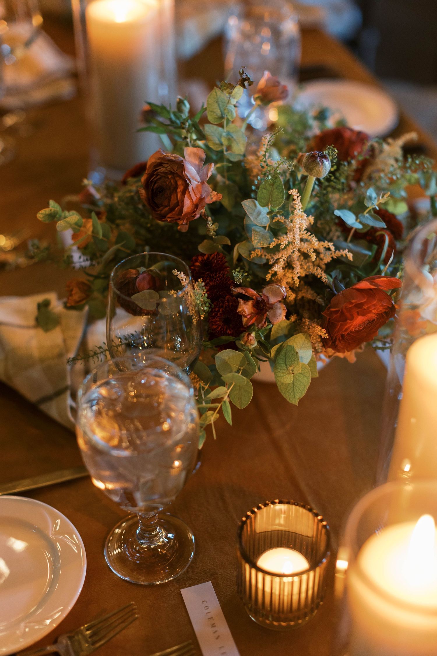 Romantic table setting with floral centerpiece, candles and glassware.