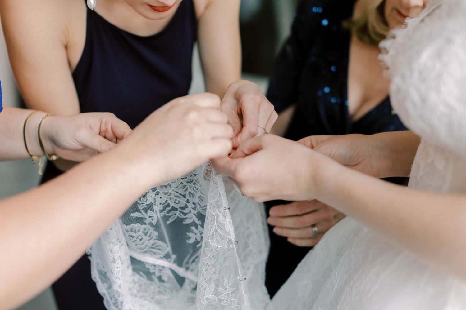 Close-up shot of hands working together to adjust wedding dress details.