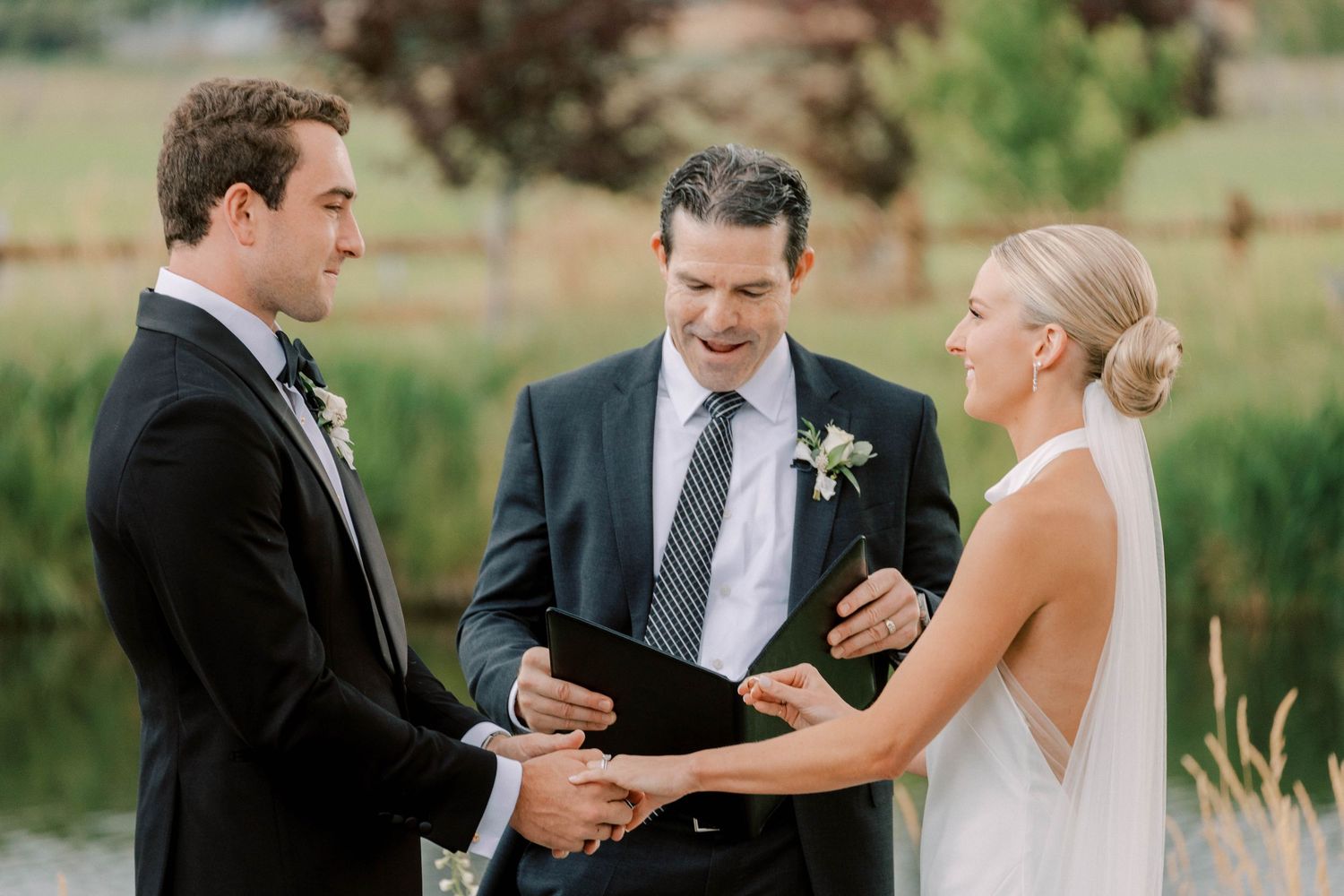 Wedding ceremony on outdoor patio with officiant conducting vows between couple.