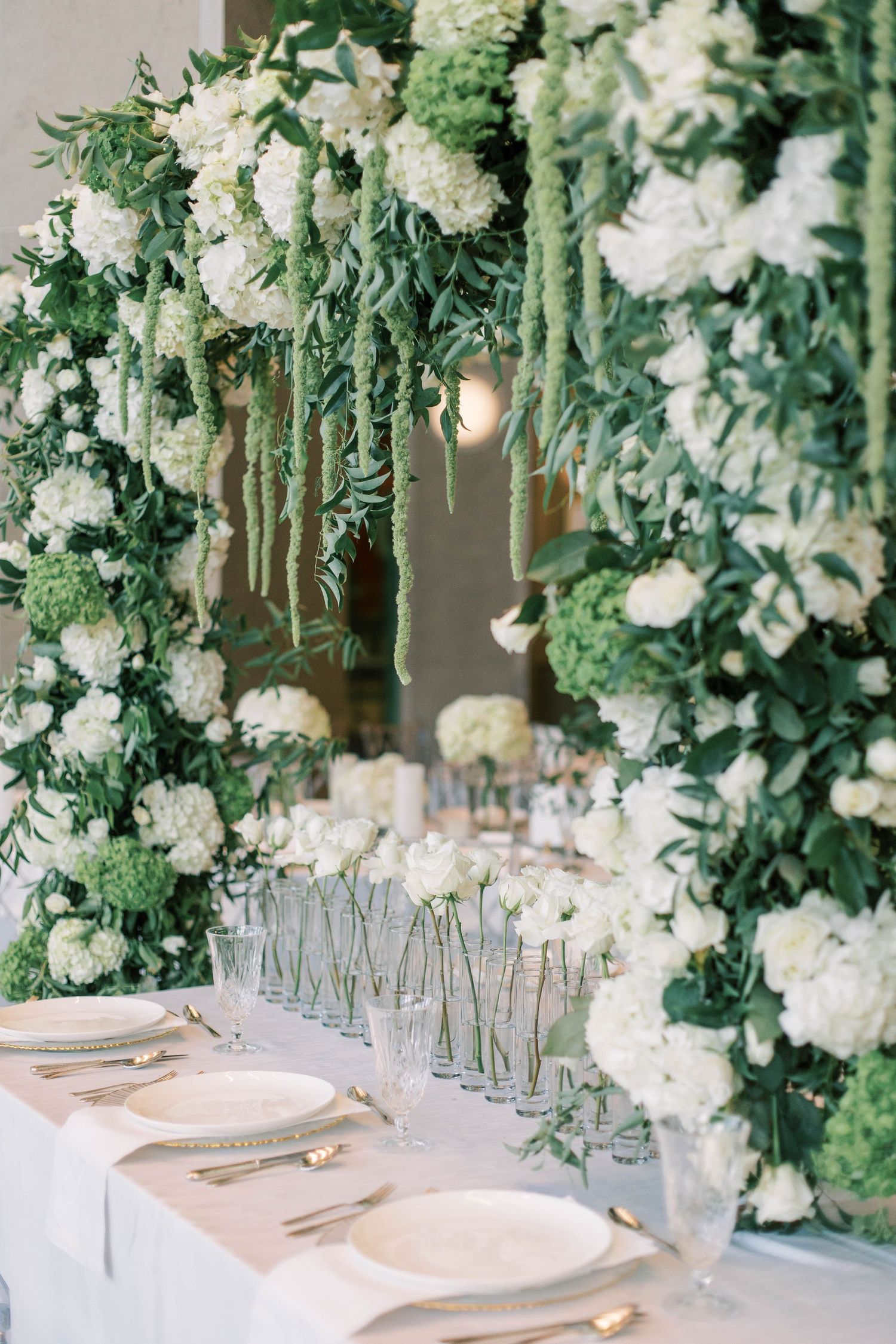 Luxurious floral wedding tablescape with cascading white flowers and greenery.