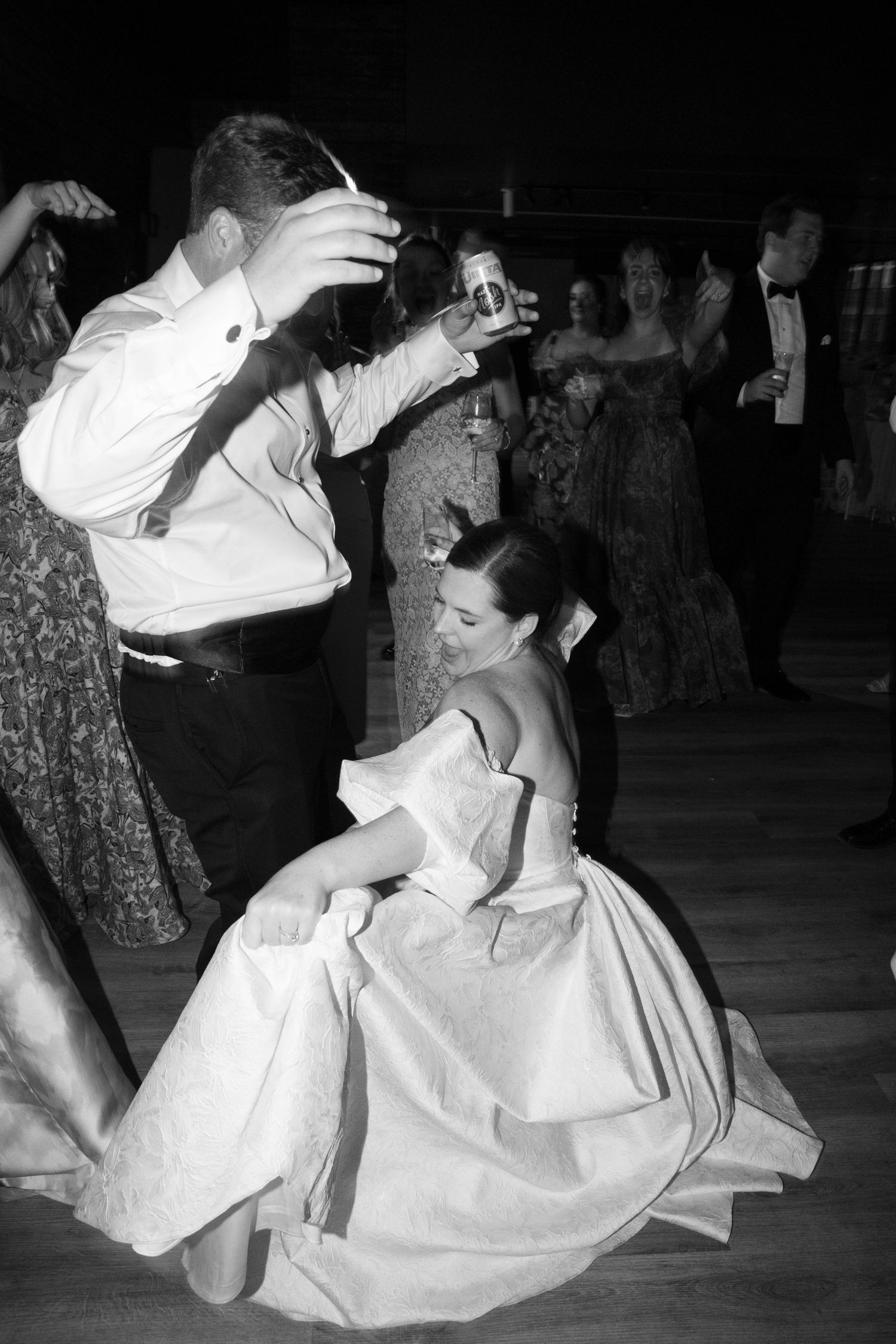 Wedding celebration with guests in formal attire dancing on wooden floor.