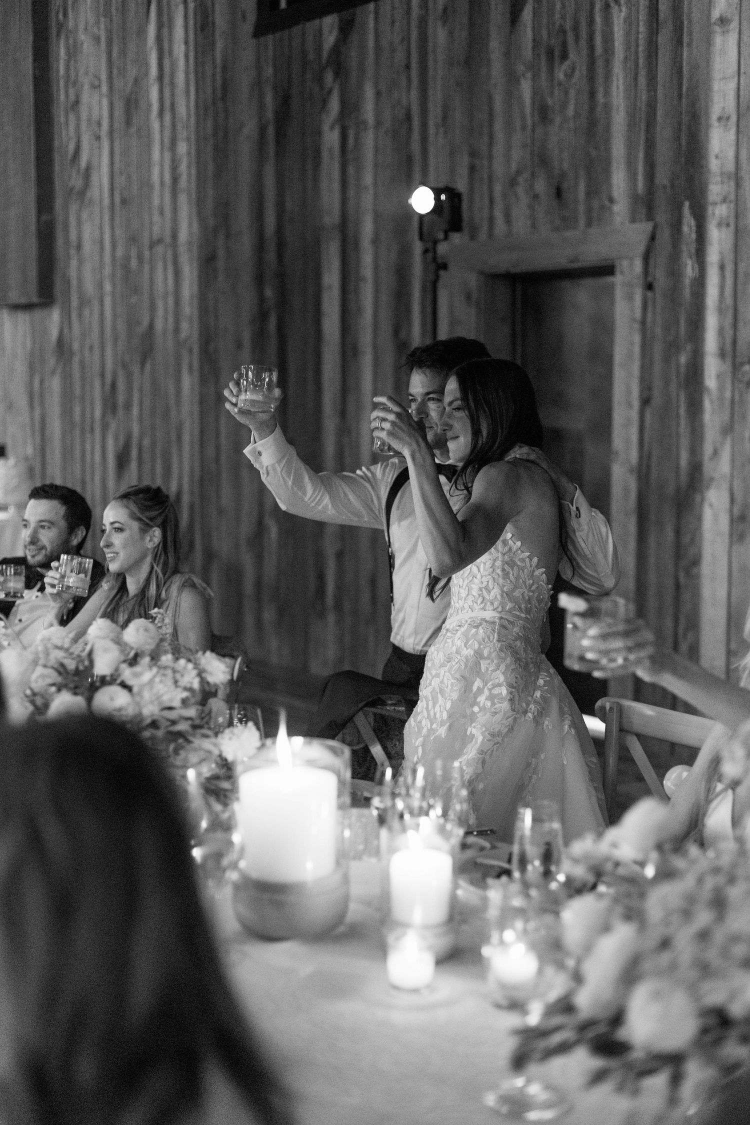 Reception guests raise their glasses during a toast at a candlelit dinner.