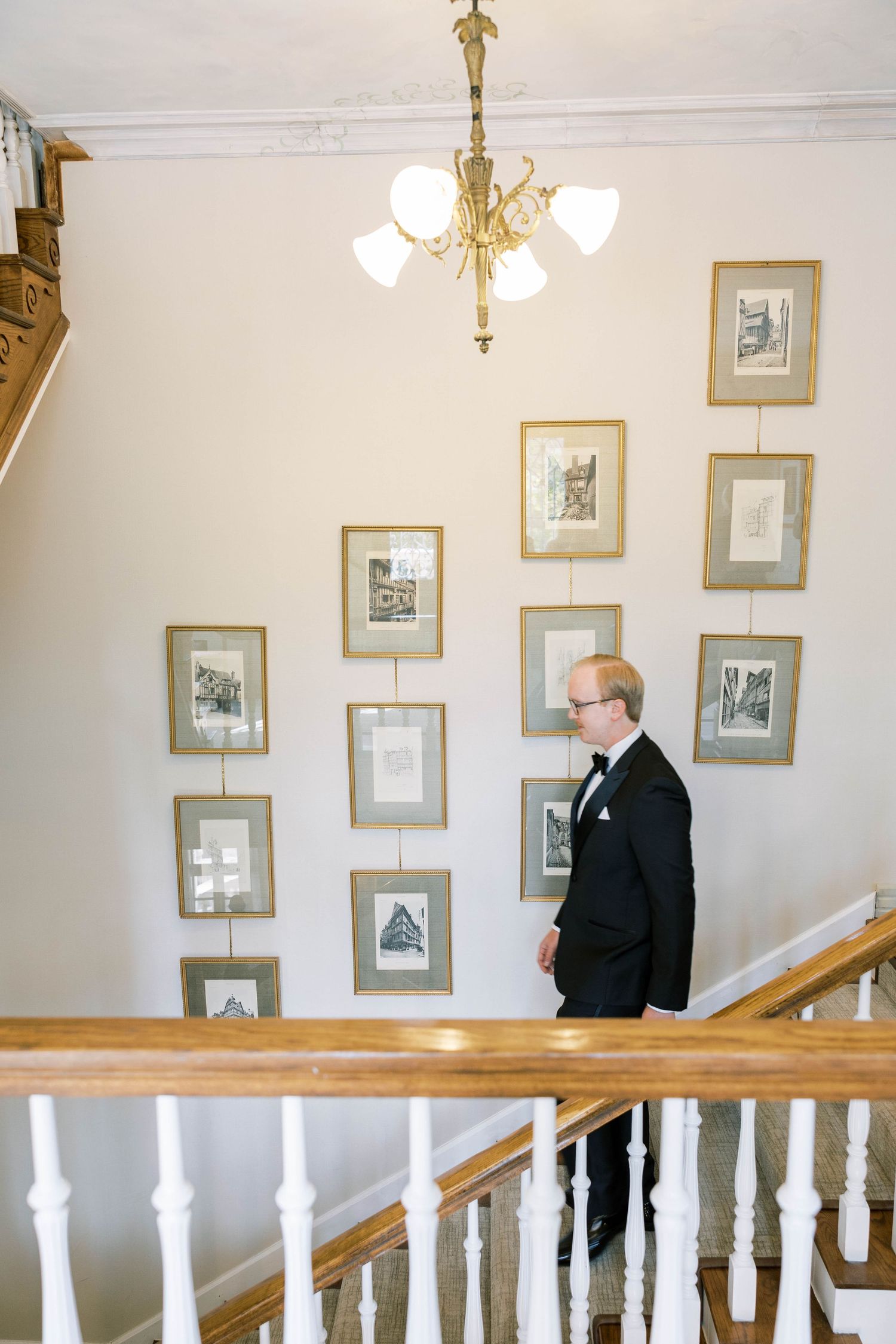 Formal attire against gallery wall with vintage photographs and elegant chandelier.