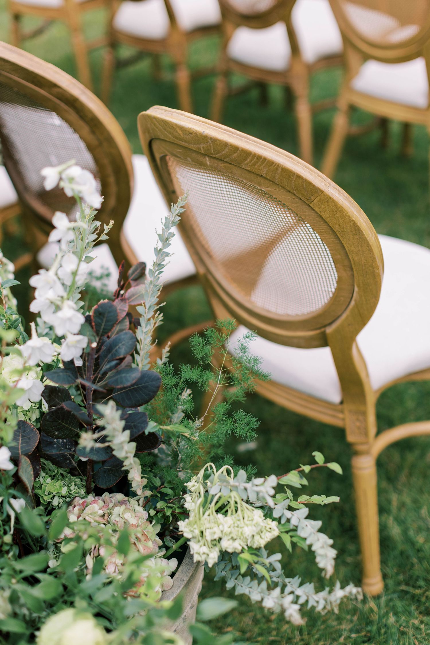 Elegant gold-framed ceremony chair with white cushions decorated with delicate floral arrangements.
