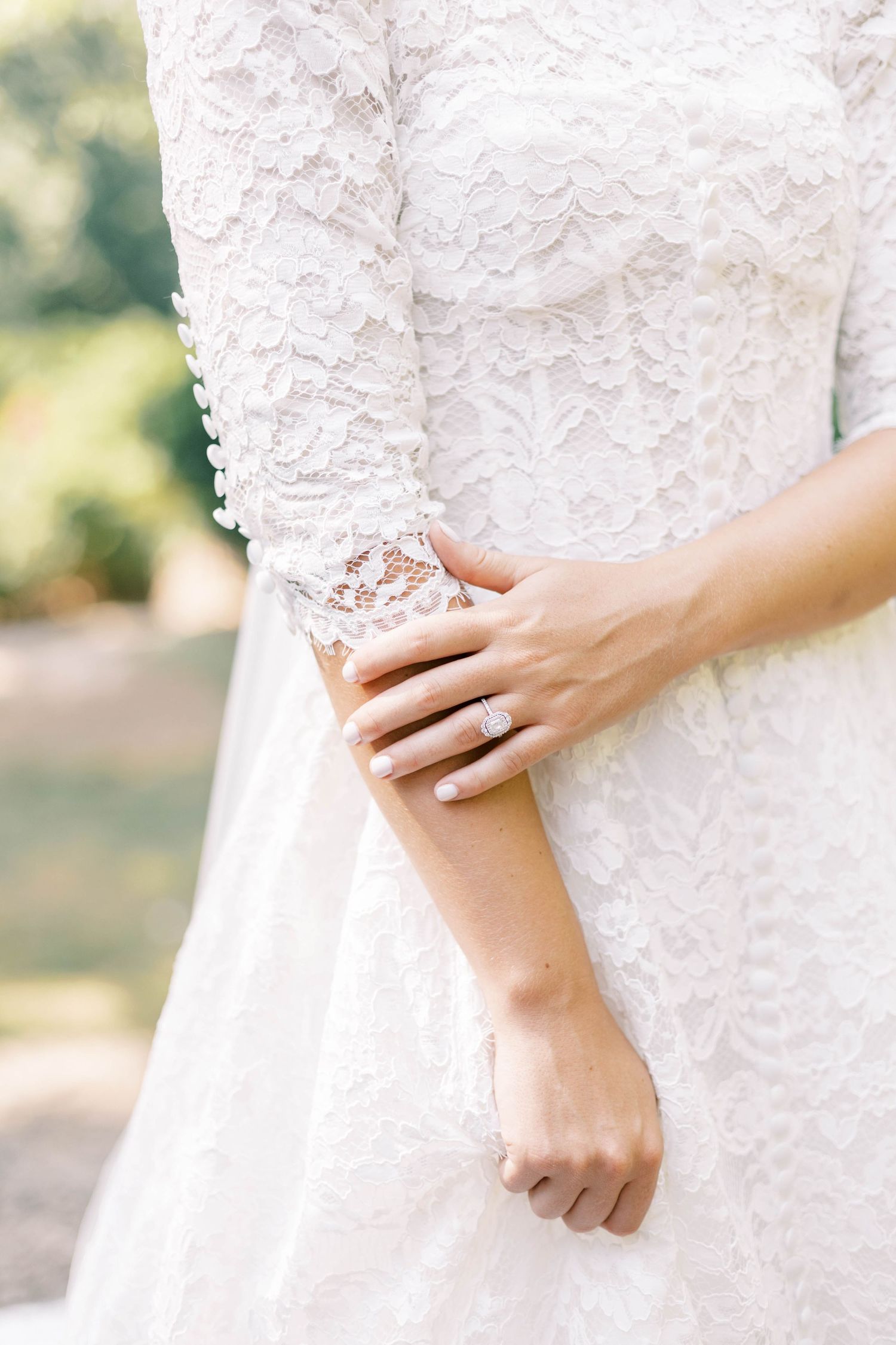 Delicate lace detail of wedding dress sleeve with hands elegantly crossed.