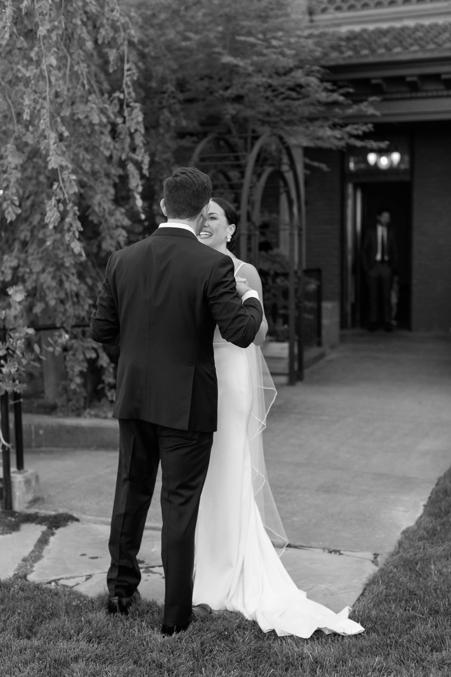 Intimate black and white portrait of couple embracing on garden path.