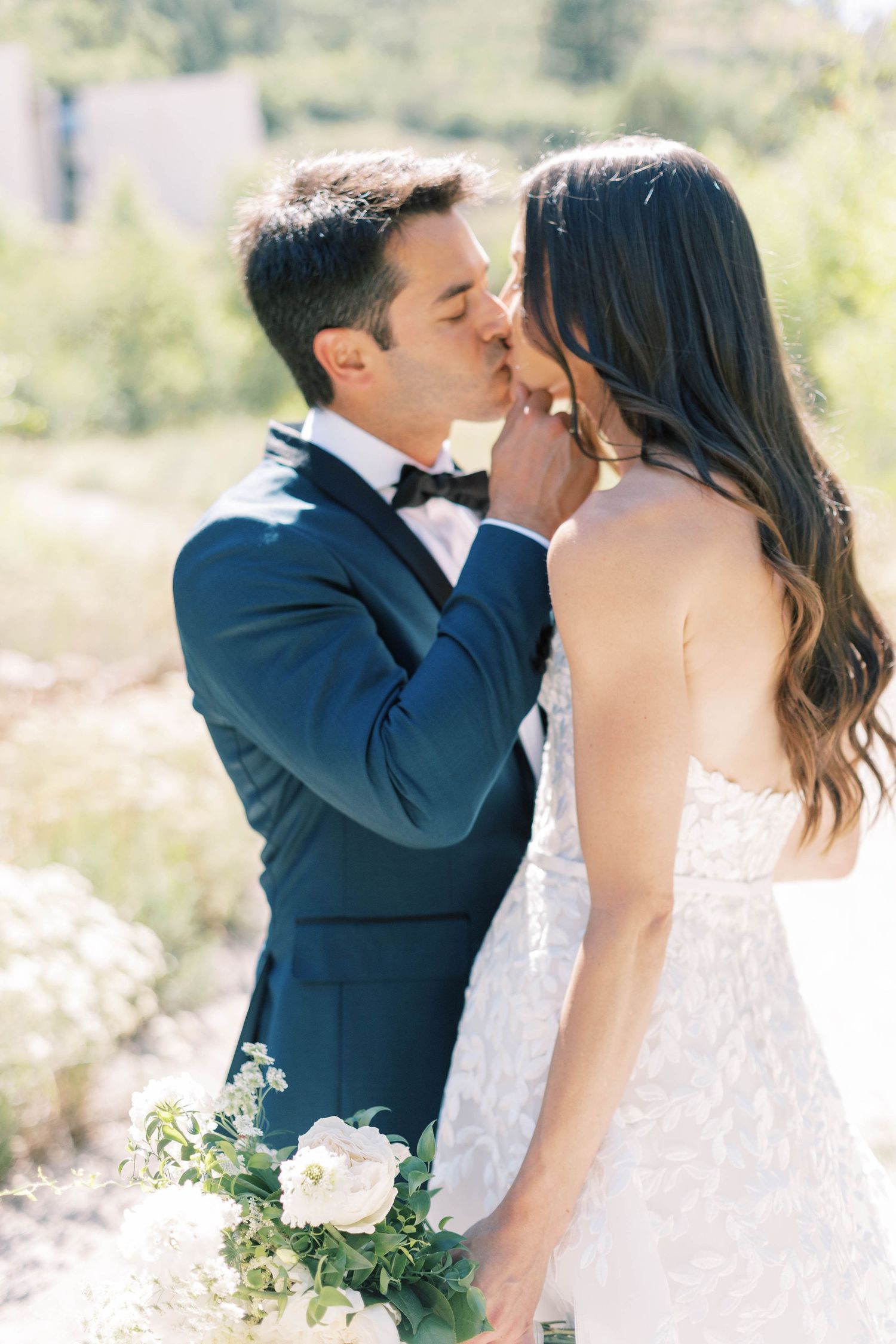 Romantic kiss between newlyweds in mountain setting.