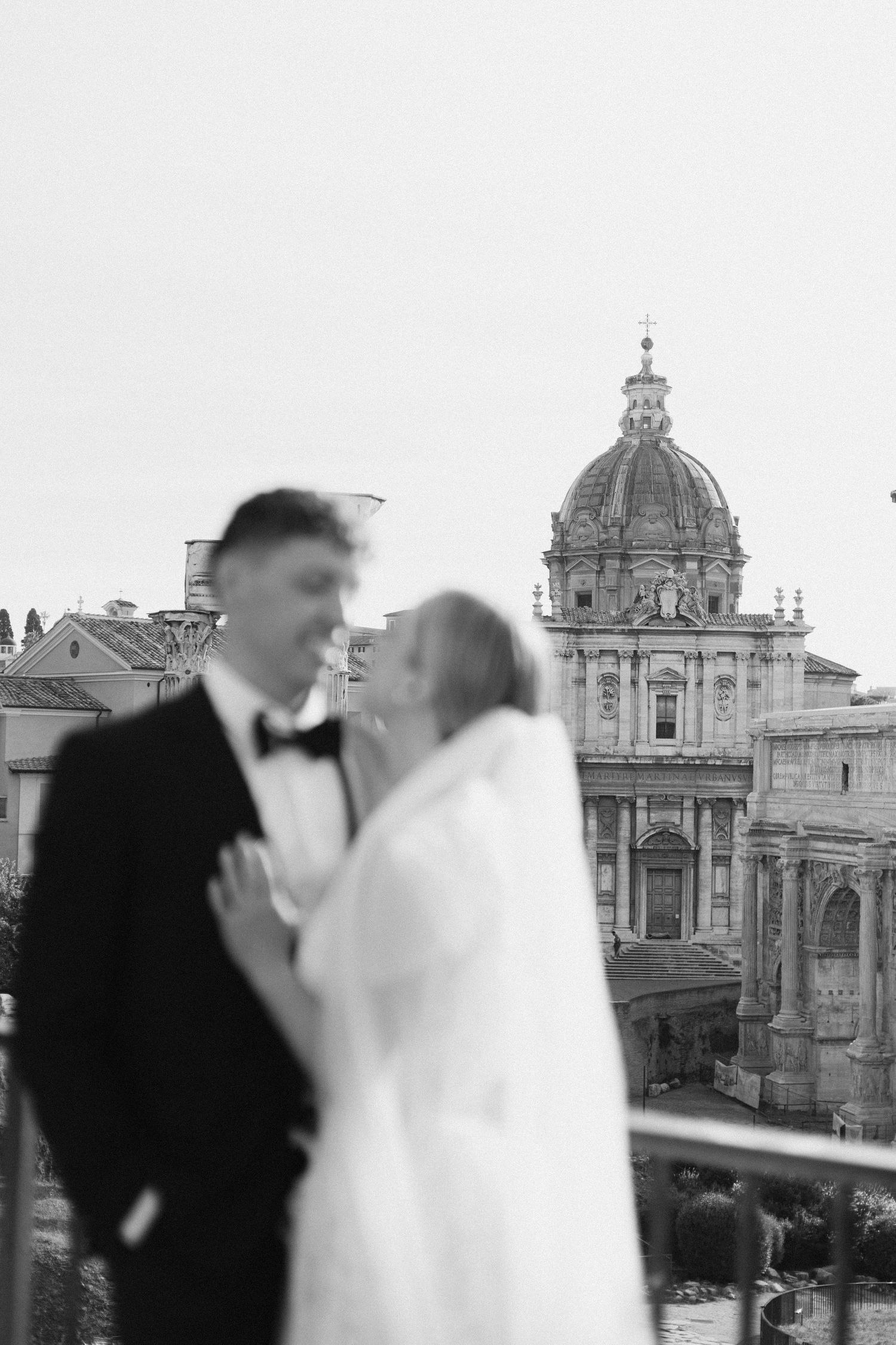 Intimate wedding portrait with the iconic Roman Forum church dome in soft focus background.