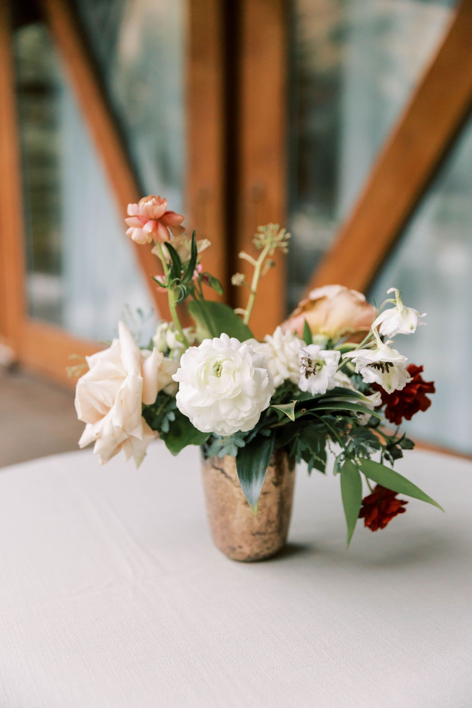 Elegant floral arrangement with white roses and pink blooms in a metallic vase on a white tablecloth.
