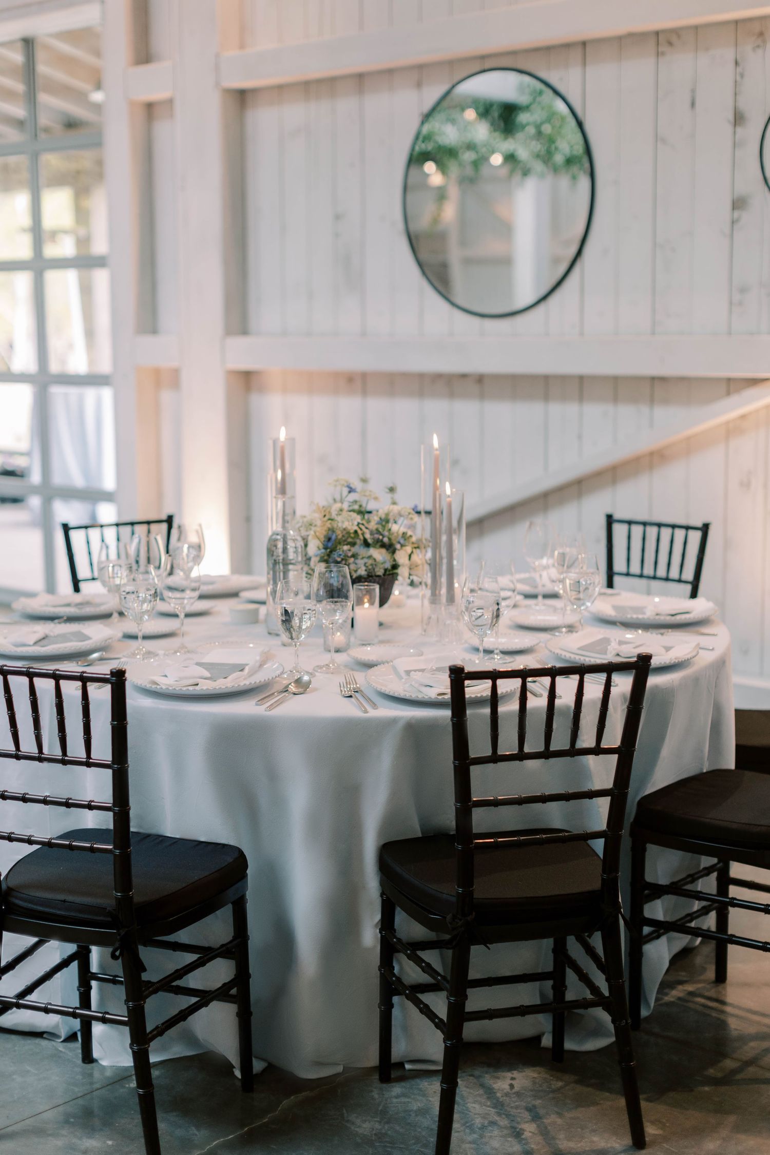 Round reception table with white tablecloth, black chiavari chairs and elegant place settings.