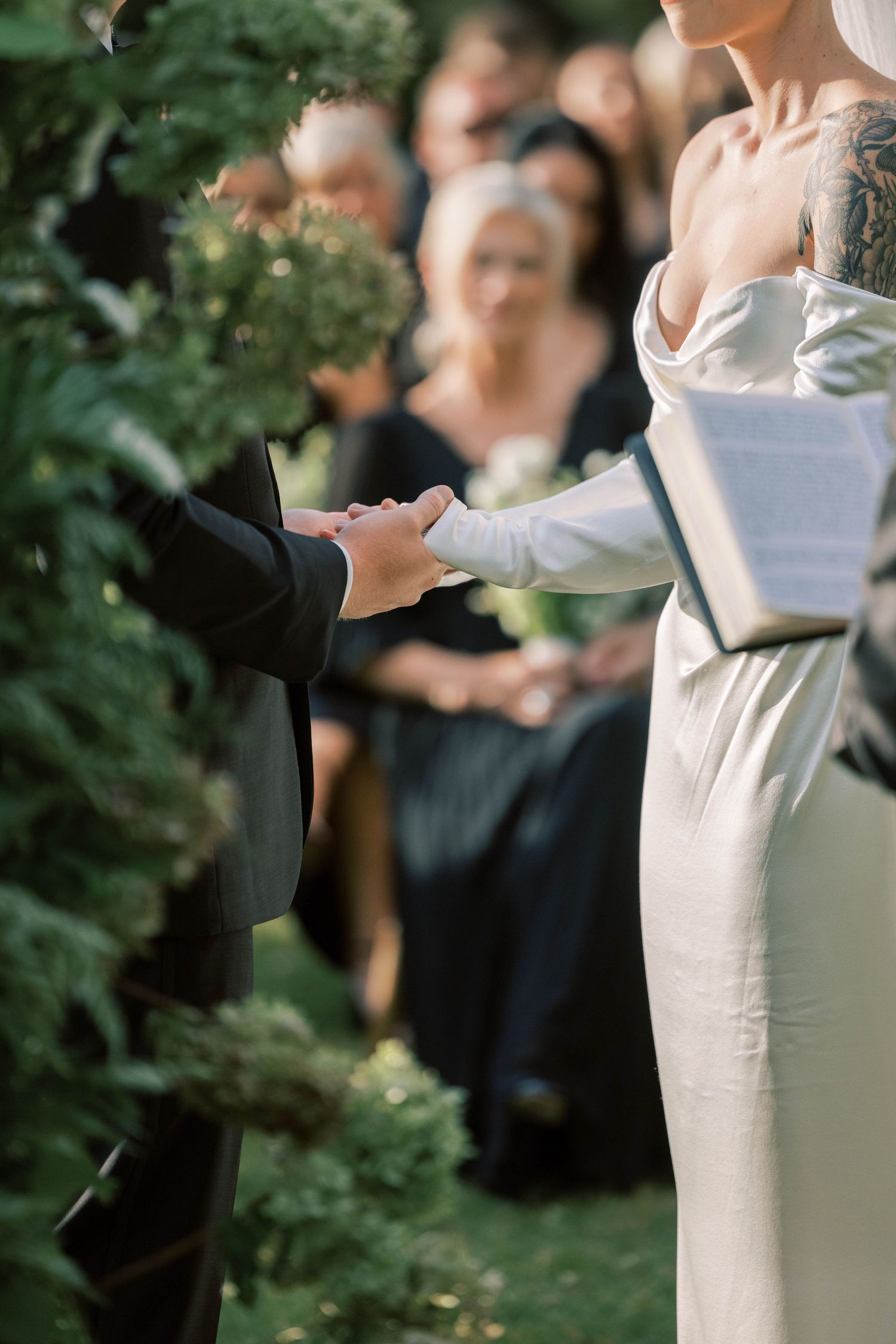 Close-up of wedding ceremony showing hands joined during vow exchange with white bridal gown detail.