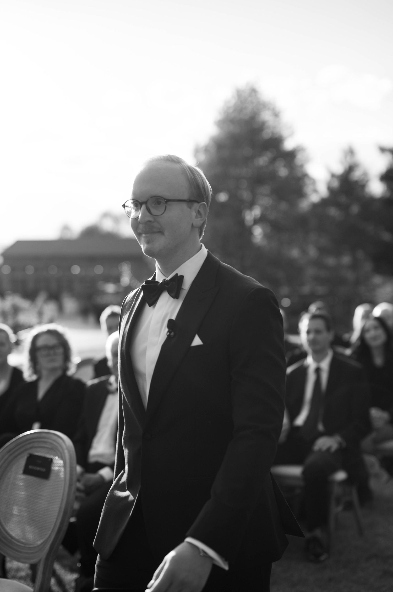 Classic black and white portrait of someone in formal attire at an outdoor event.