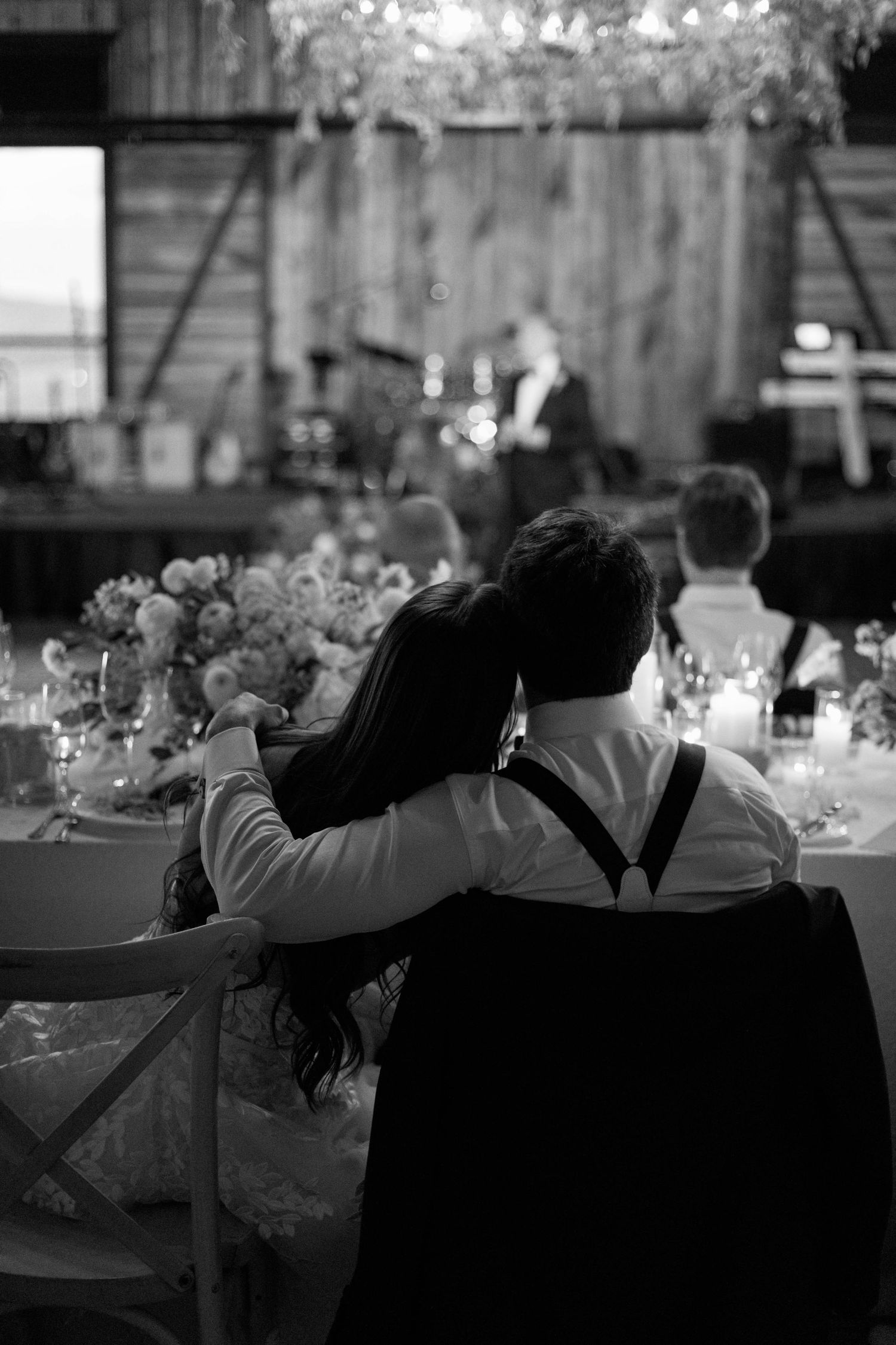 Couple watching speeches together at their rustic barn wedding reception.