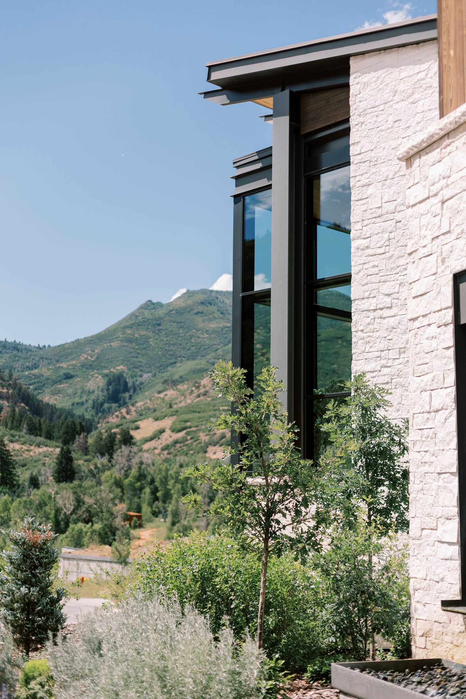 Modern white stone building with floor-to-ceiling windows framing mountain views.