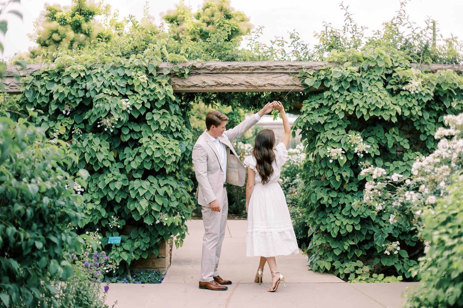 Romantic Red Butte garden scene with a couple embracing under a lush green pergola covered in climbing vines.