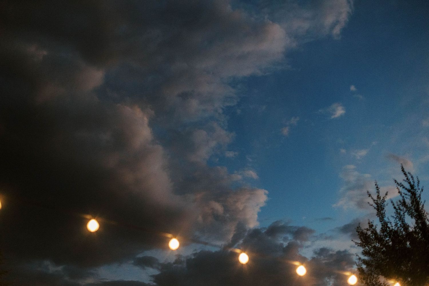 String lights glowing against a dramatic evening sky with clouds.