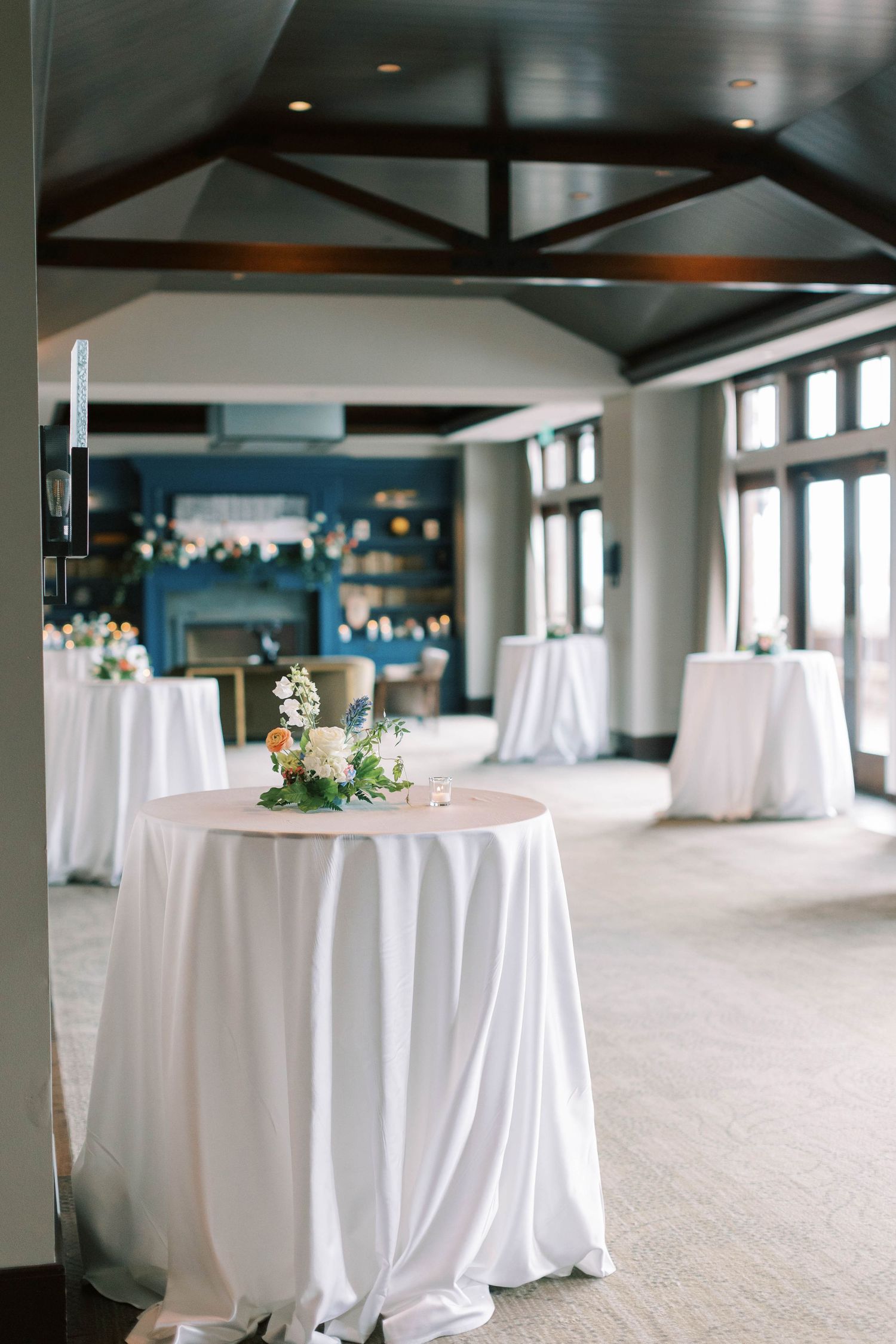 Elegant reception venue with white tablecloths and dark wooden beams featuring modern decor.