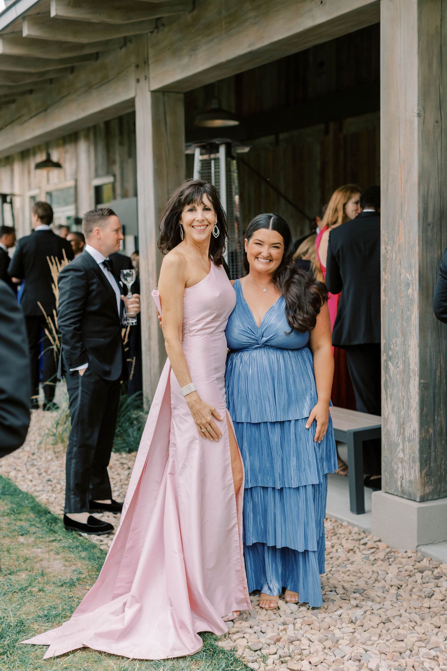 Wedding guests in pink and blue formal dresses at outdoor venue.