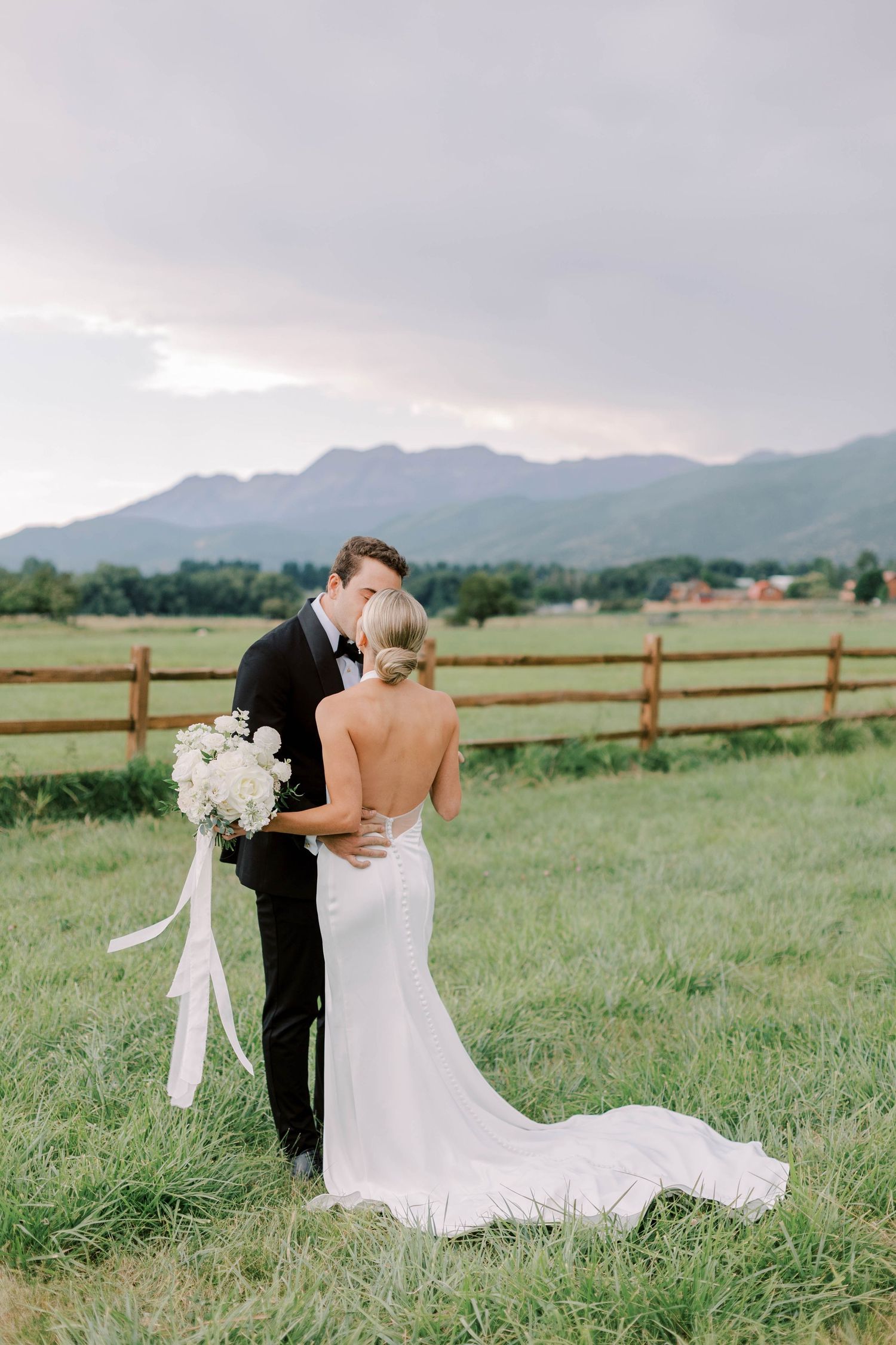Intimate wedding moment captured against mountain backdrop with white floral bouquet.