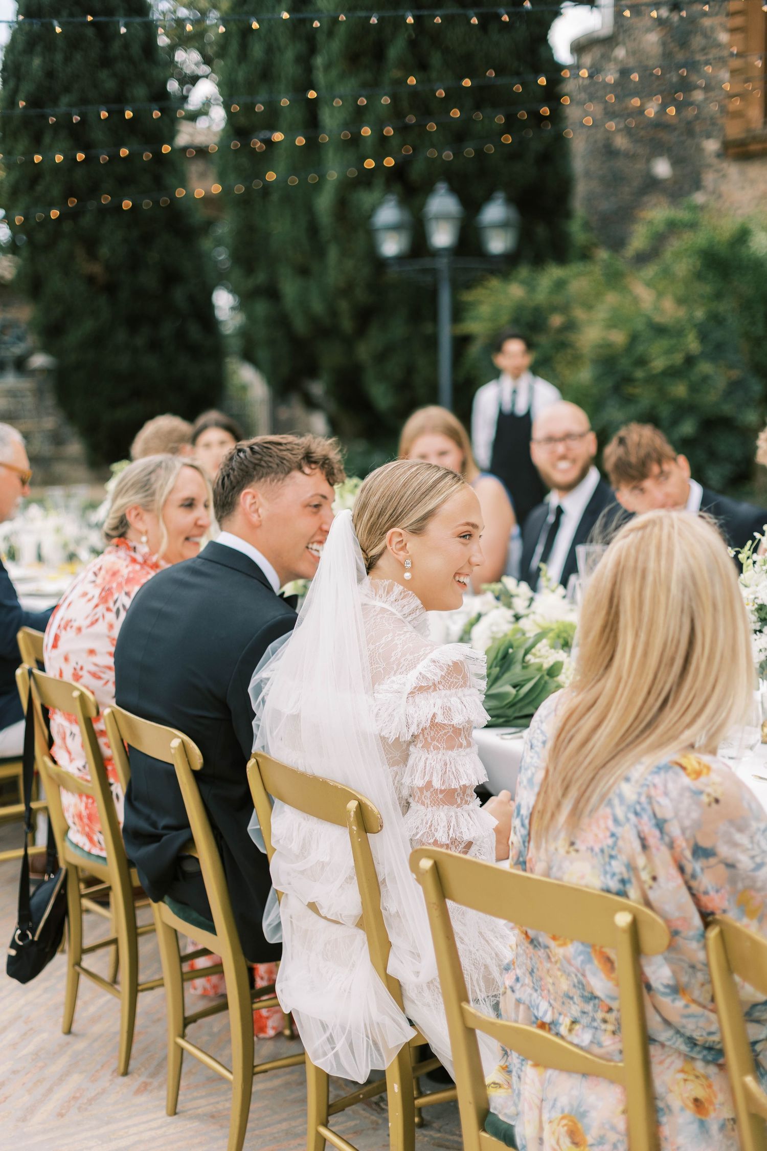 Outdoor wedding reception with guests seated at long tables under string lights at castello della castellucia.